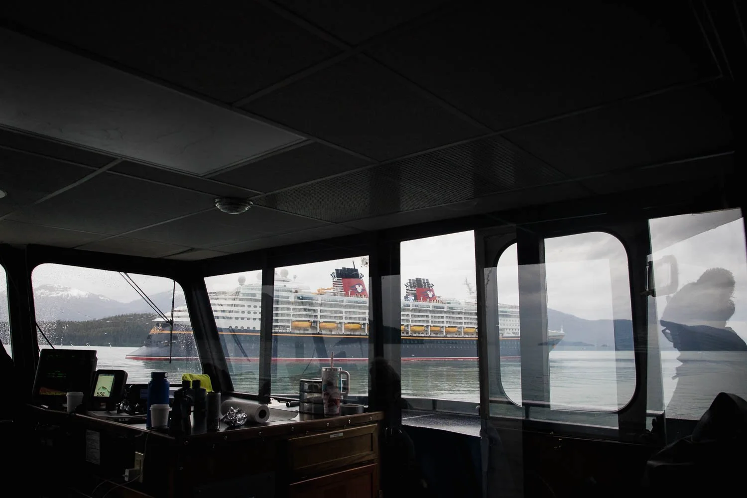 View of the Disney Wonder through the glass windows of an excursion boat in Alaska.