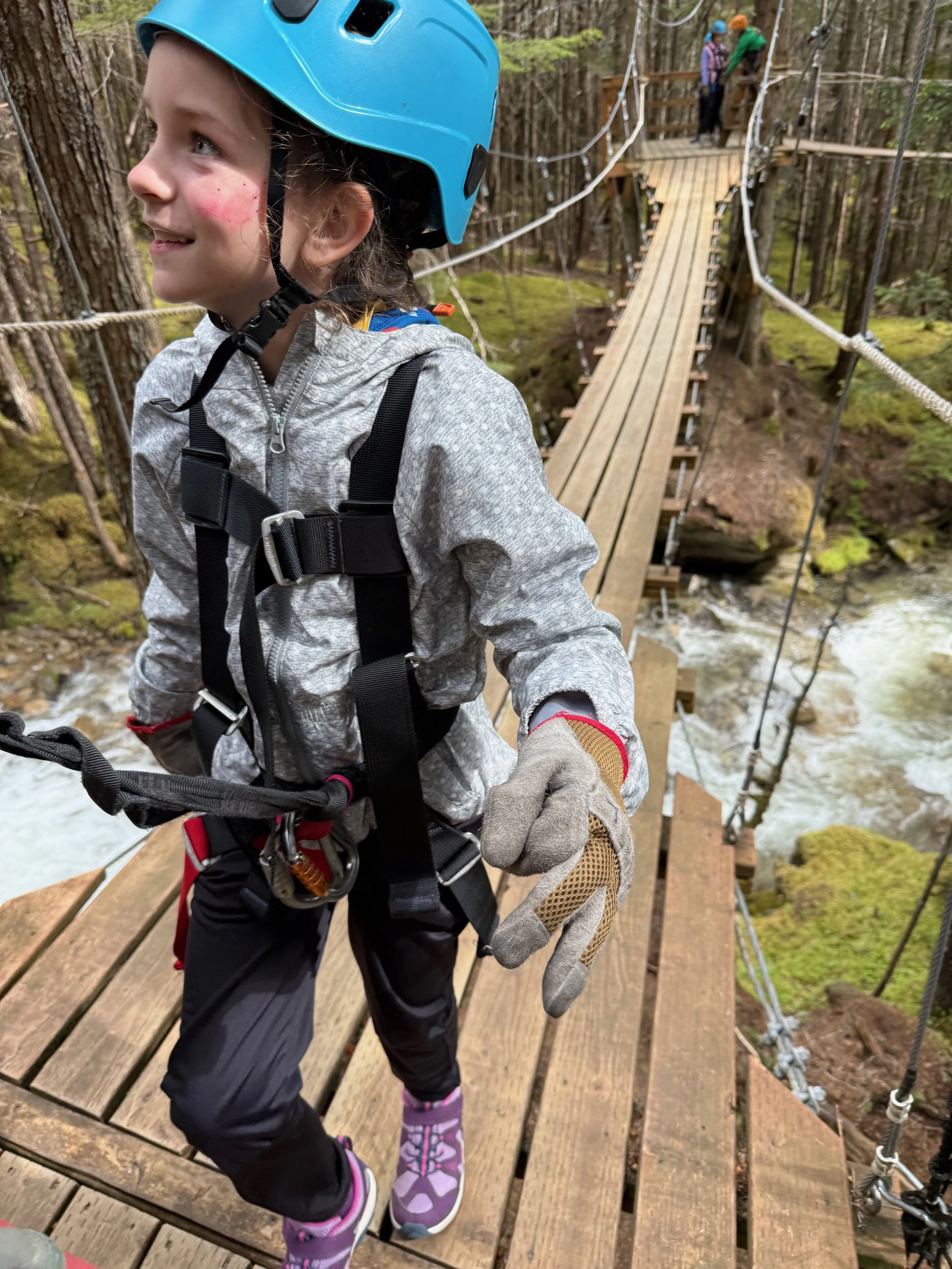 Little girl walks across a suspension bridge over Grizzly River Falls in Alaska.
