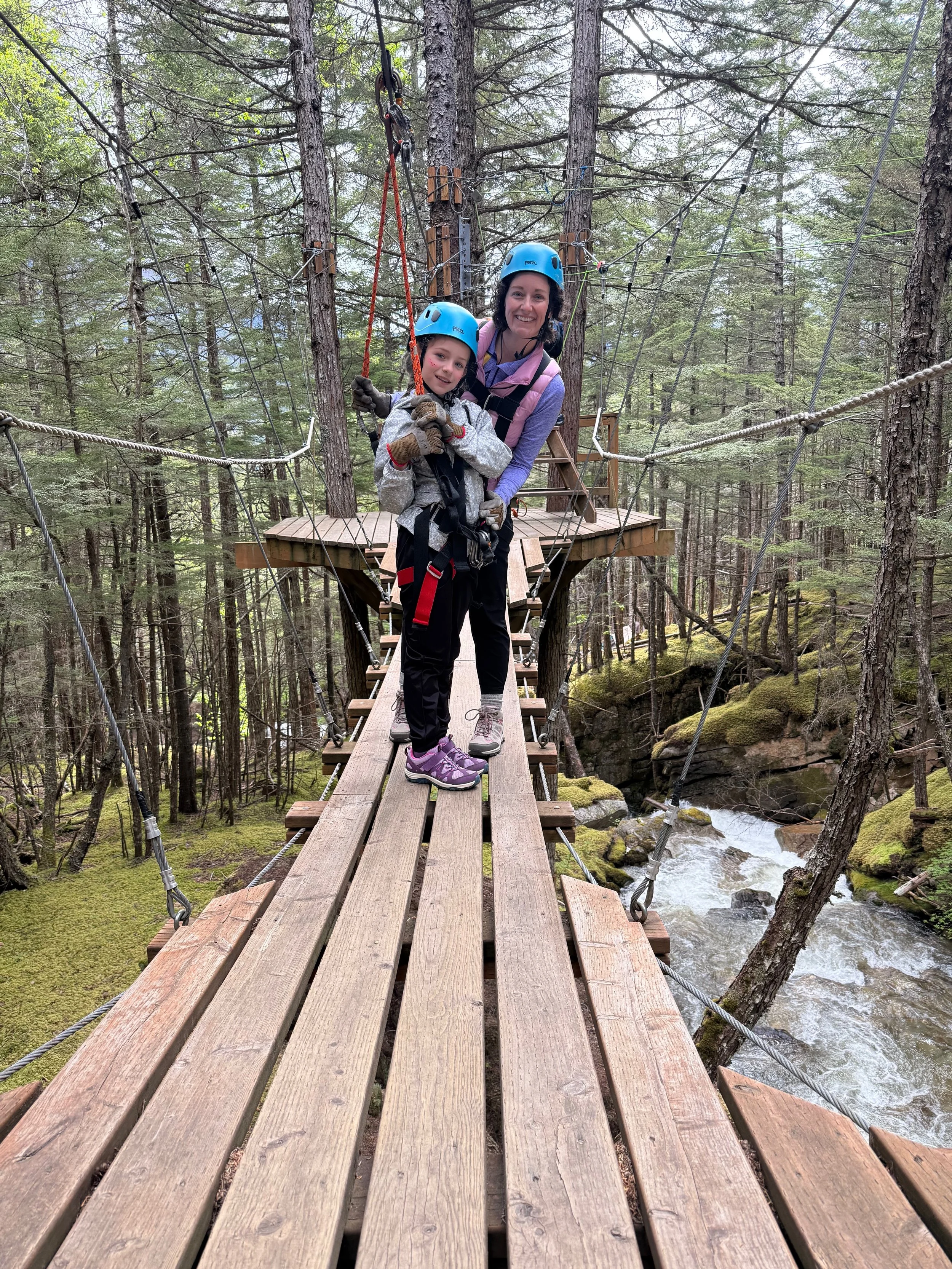 Mother and daughter pose on a suspension bridge in Alaska.