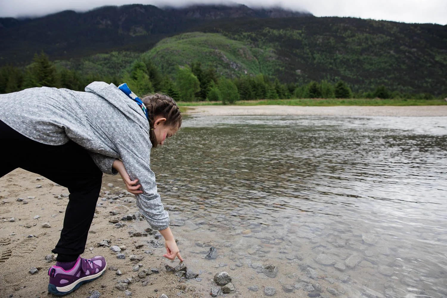 Little girl touches the ice cold water in Skagway, Alaska.