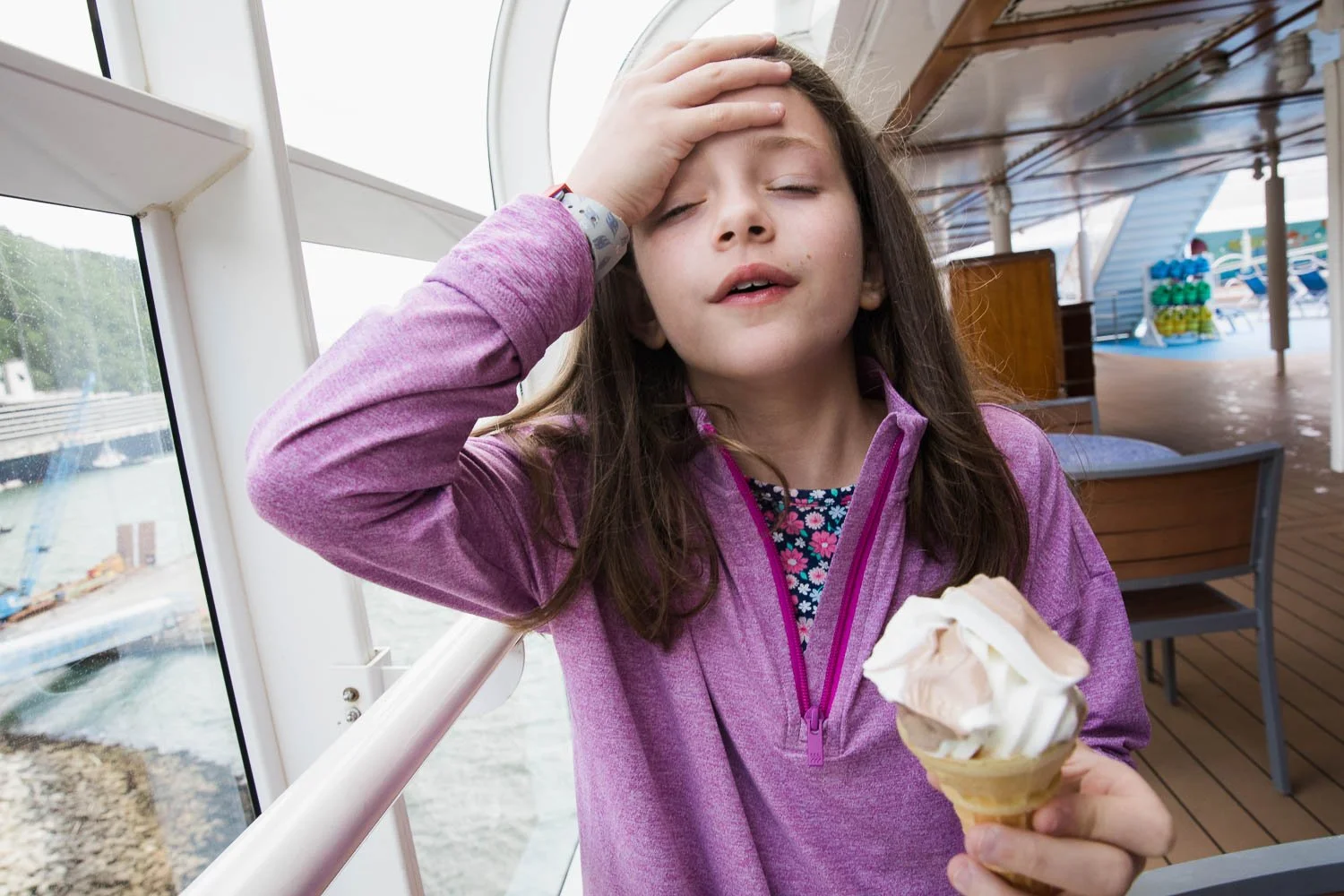 Girl grabs her head after getting a brain freeze from her ice cream cone.