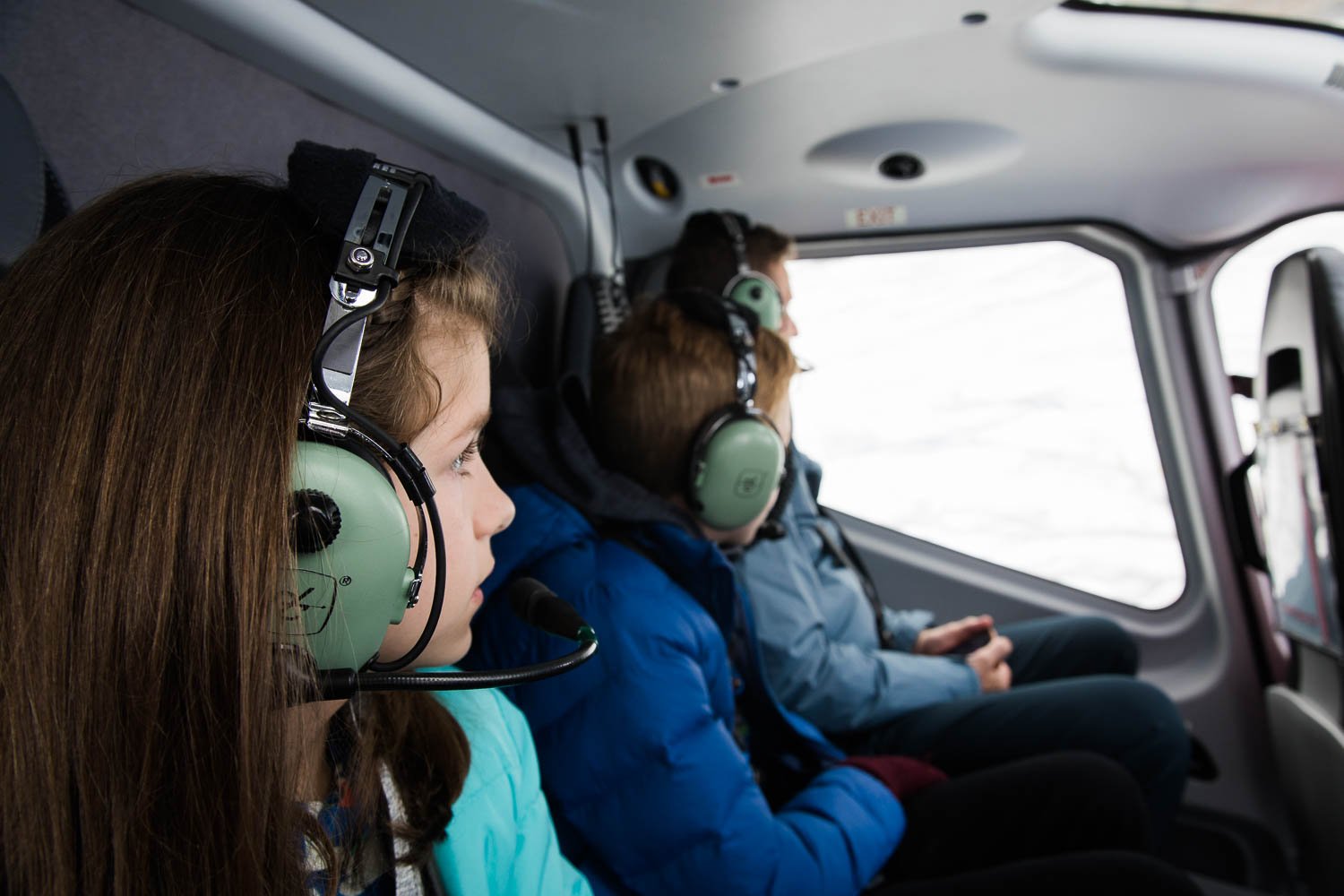 Family looks out over Alaska from a helicopter.
