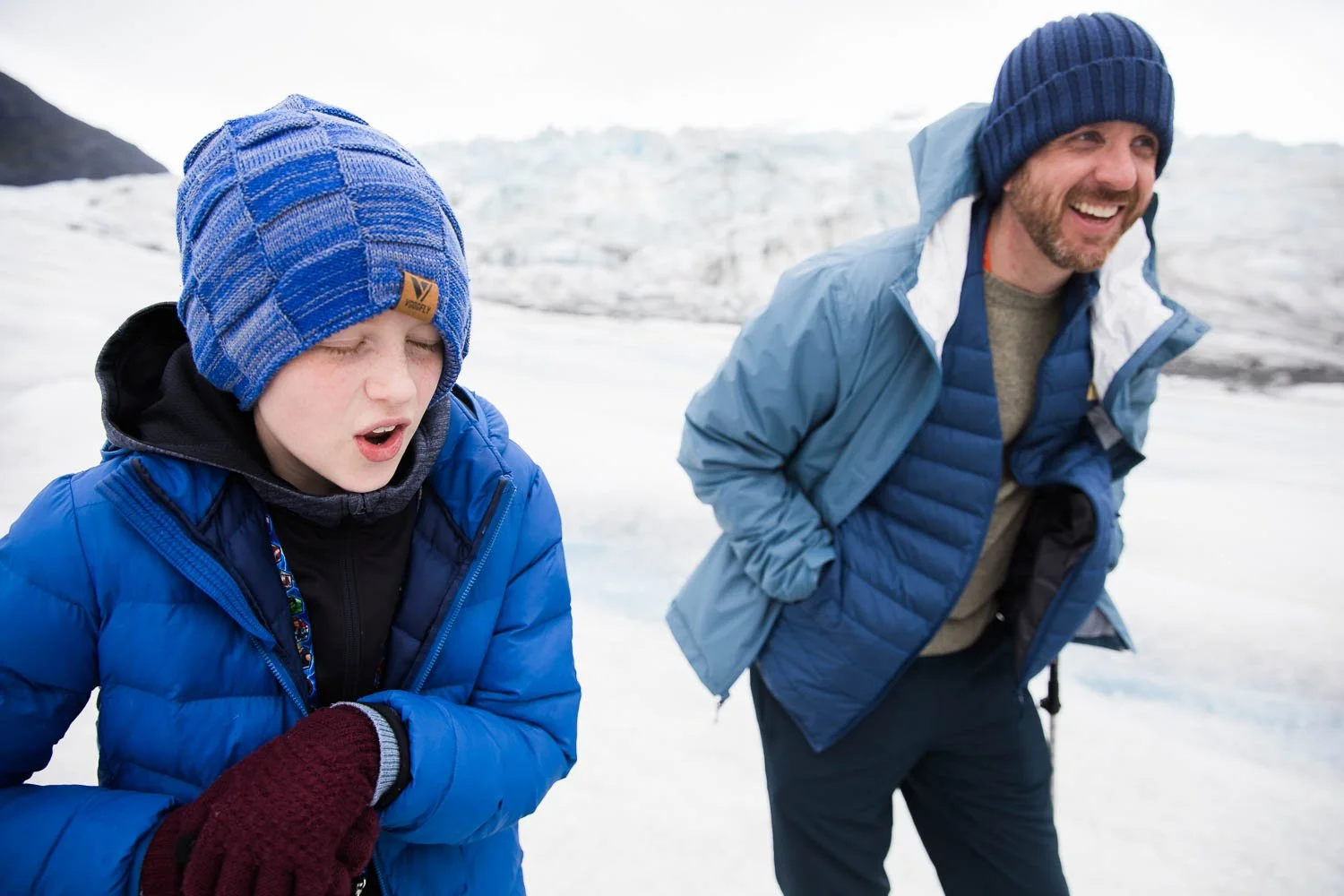 Father and son laugh together on top of an Alaskan Glacier.