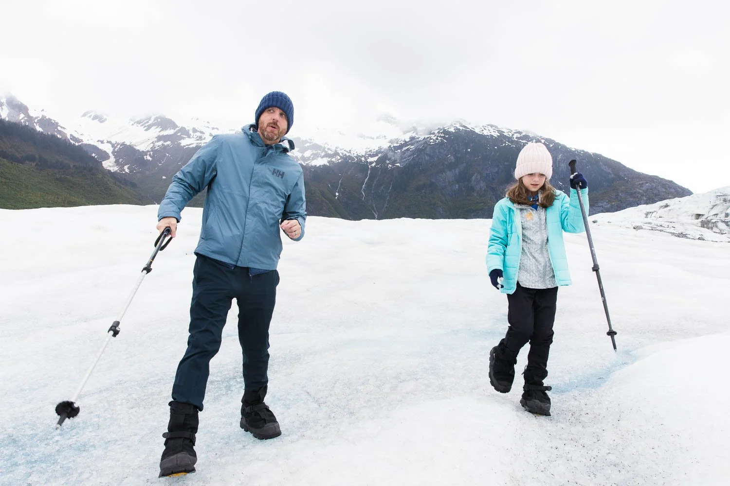 Father and daughter walk across a glacier in Alaska.