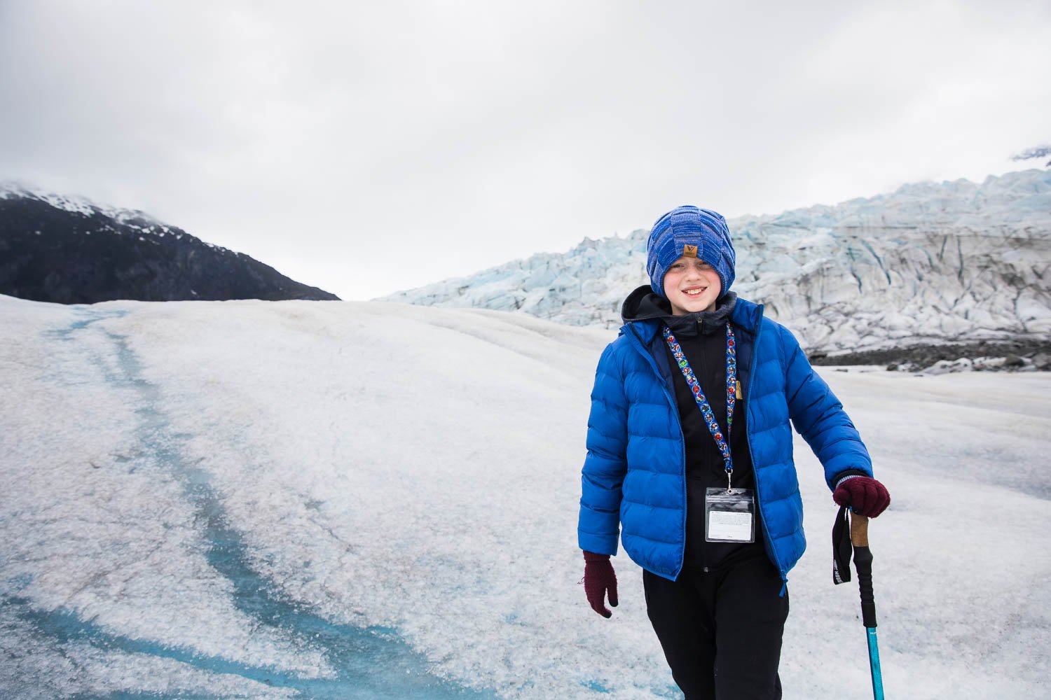 Kid poses with his walking stick on a glacier in Alaska.