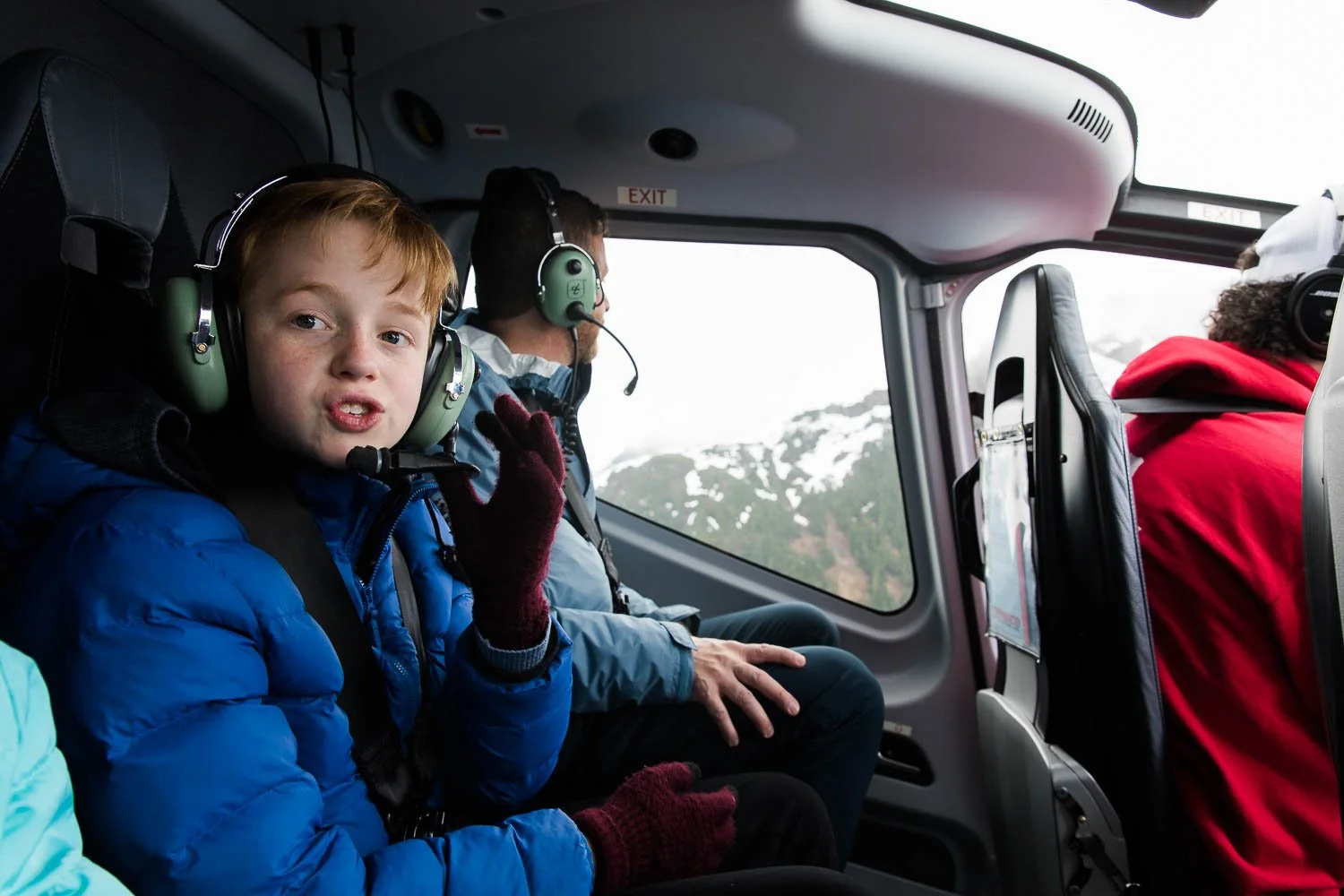 Boy talks on headset on a helicopter tour of Alaska glaciers.