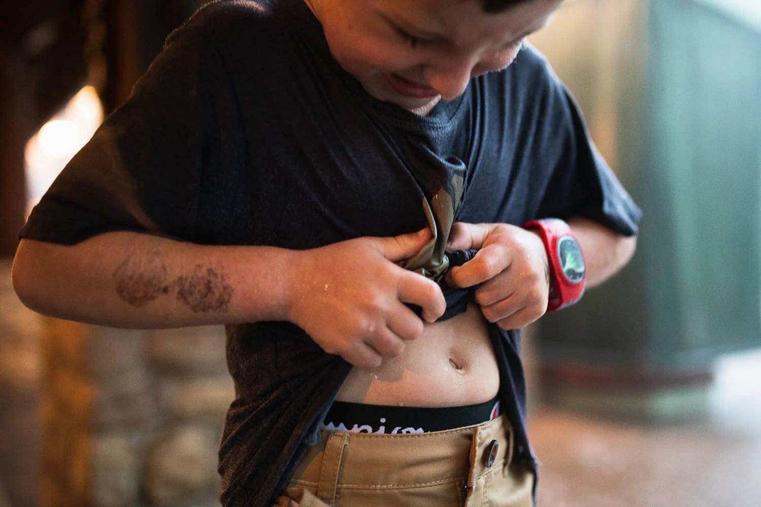 Boy wrings water out of his shirt after playing in the rain.