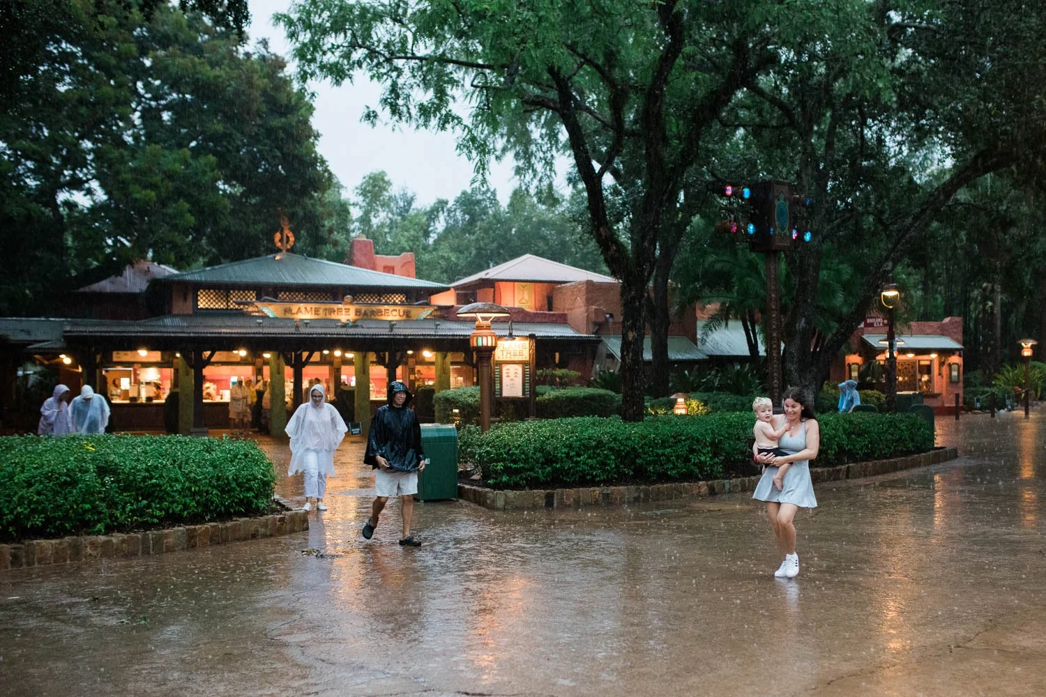 Mom walks with toddler in the rain at the Animal Kingdom.