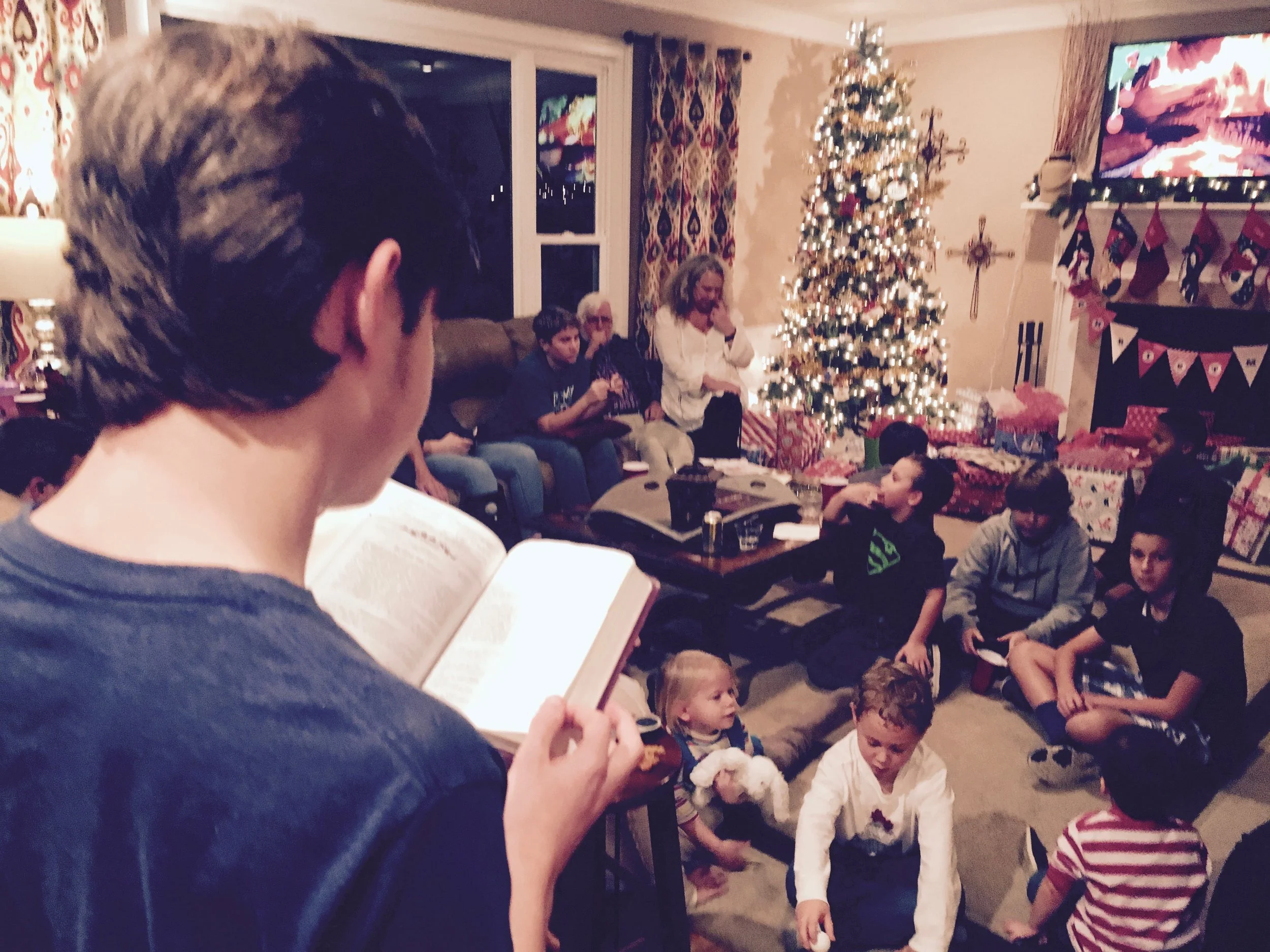 TJ reading the Christmas story as the kids wait to dive into presents. It was too hot for a real fire. So, we streamed one from YouTube.