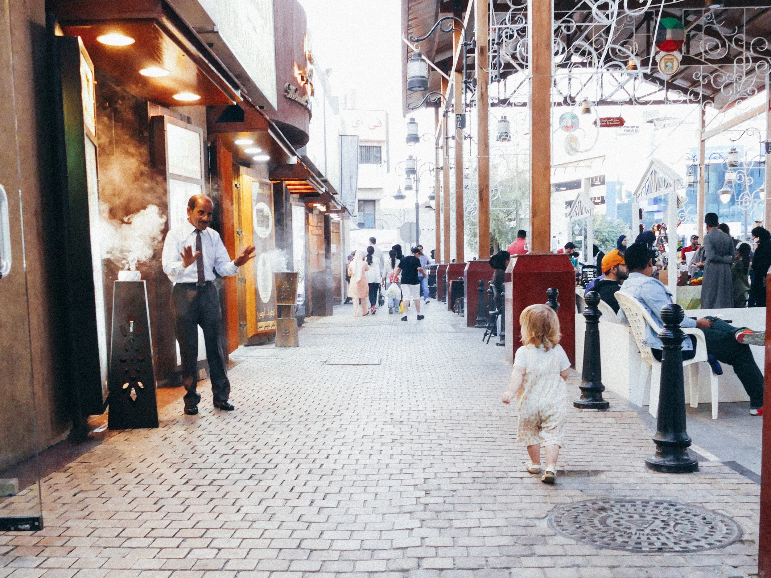 A little girl toddler walks by a friendly man in the Friday Market Souq, Kuwait, Persian Guld, Middle East, Asia.
