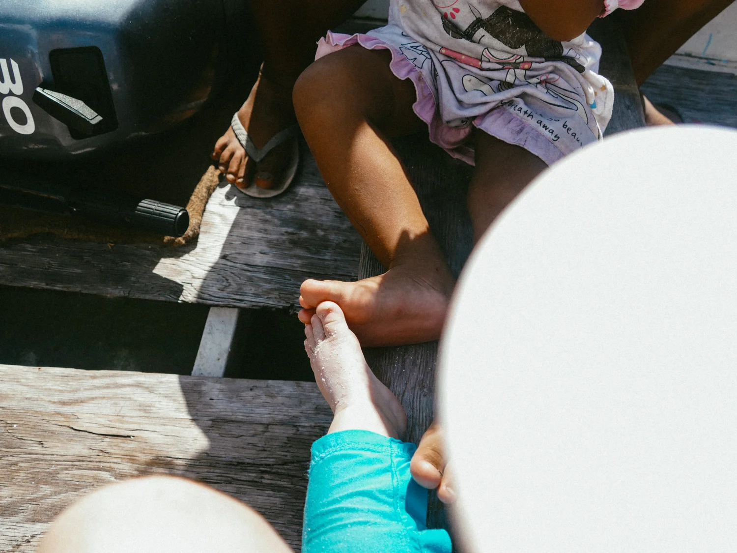 Two baby feet in a boat, Tikehau, Tuamotus, French Polynesia, South Pacific.