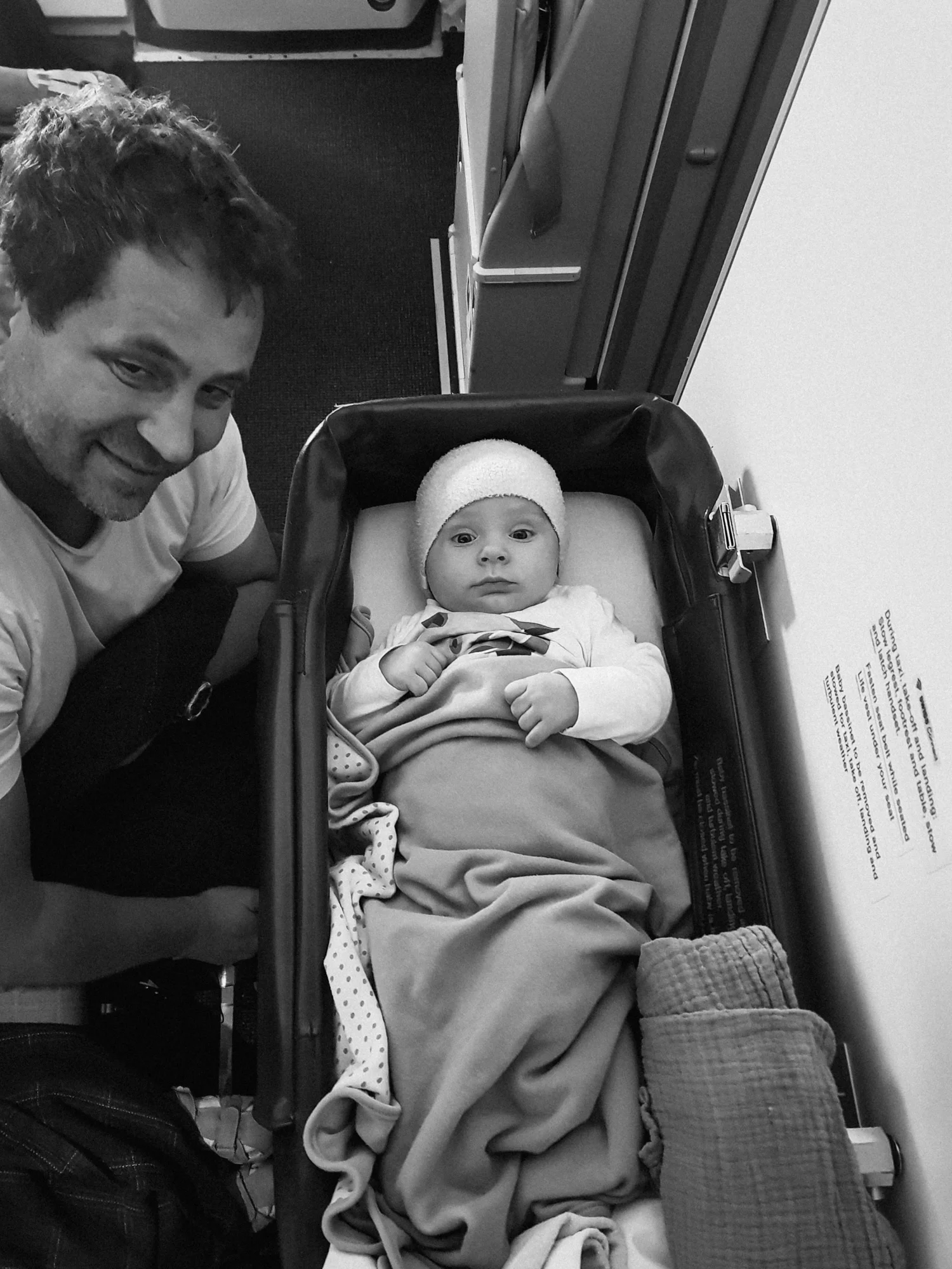 A baby looks up from an airplane bassinet.