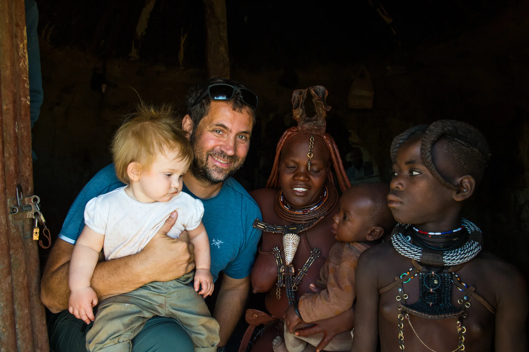 White tourist with his baby in a Himba village, Kaokoland, Namibia