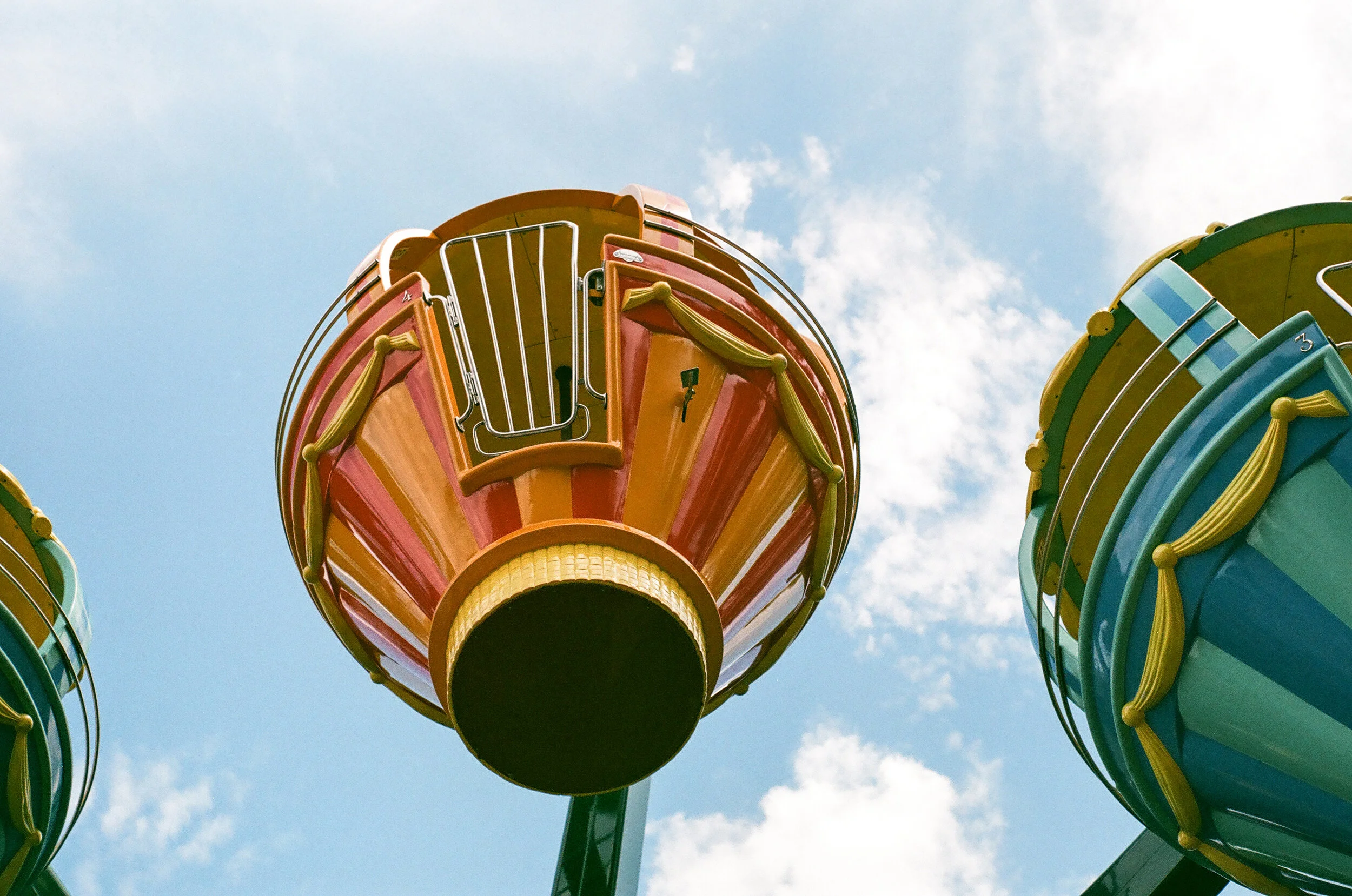 a hot air balloon themed ferris wheel at Storyland in Glen, New Hampshire. The carriage is red and orange, you can see the silver gate of the carriage.