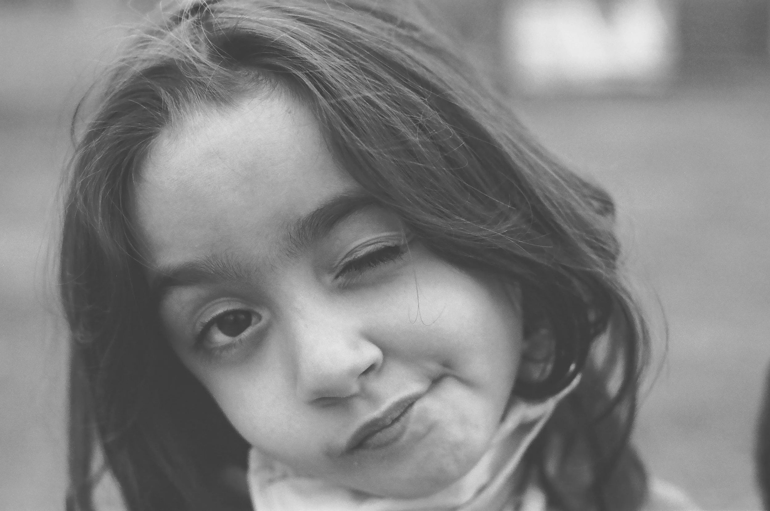 an image of a child winking at the camera. They have long wavy hair