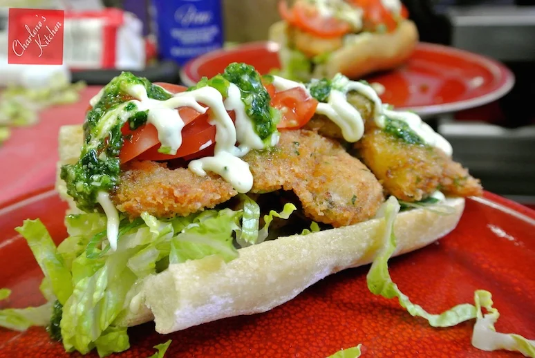 Po'boy with breaded shrimp on a ciabatta roll with lettuce, garlic aioli, spinach pesto, and tomato. Just looking at this picture made us crave these shrimp po'boys again!