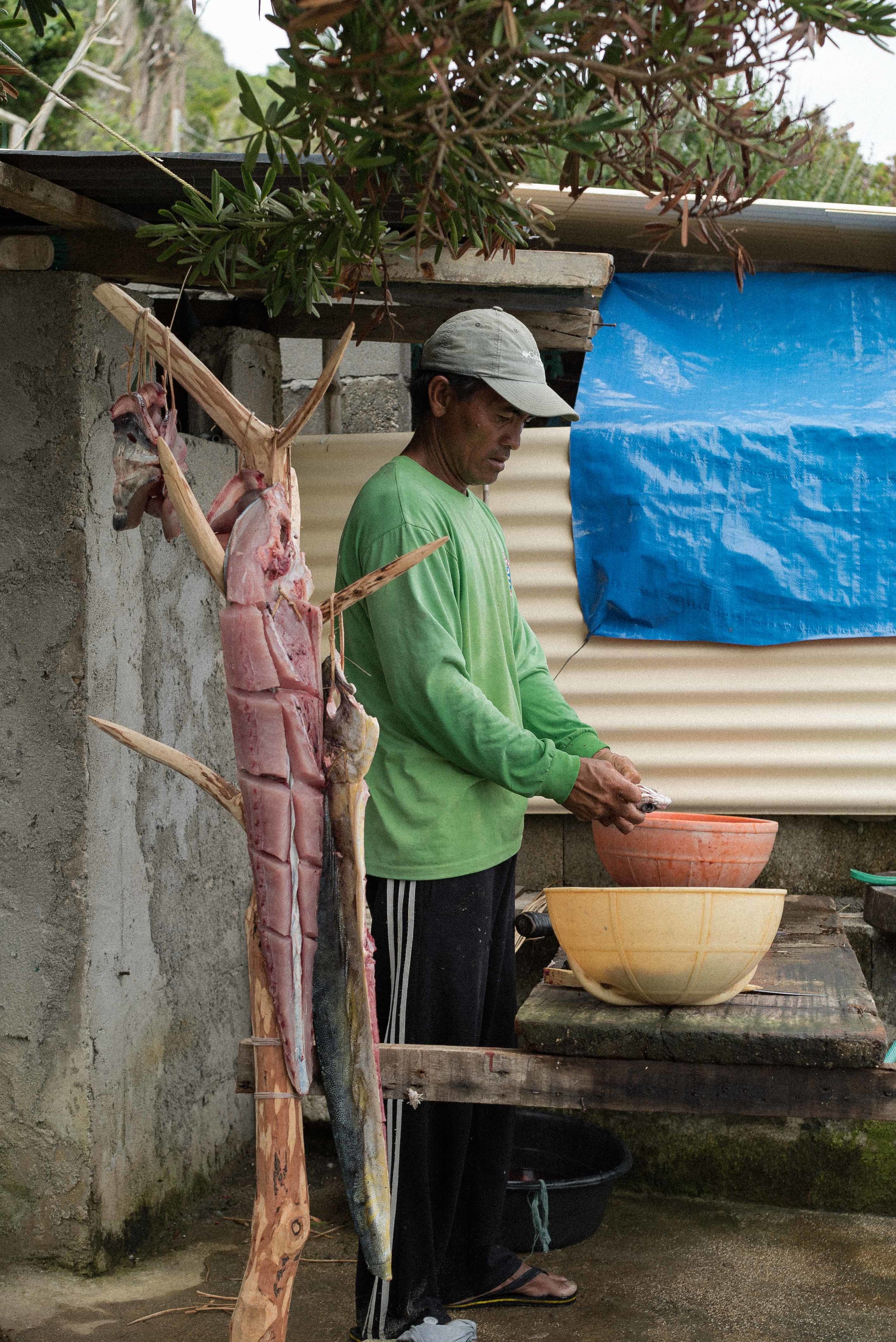  A fisherman slices and cures his morning catch. The dorados are hung outside his home to dry. 