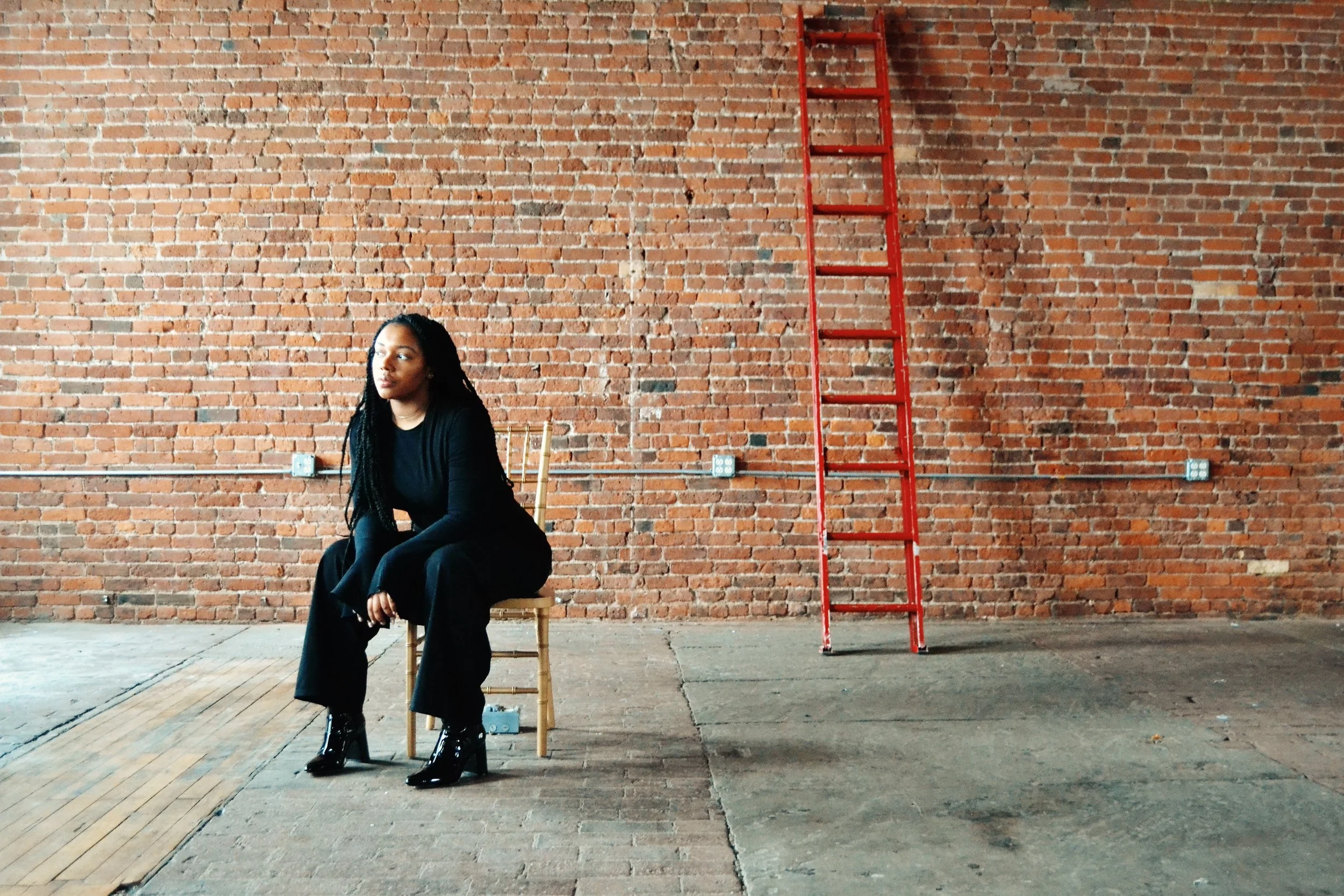 Shanelle sitting in a chair next to a red ladder.