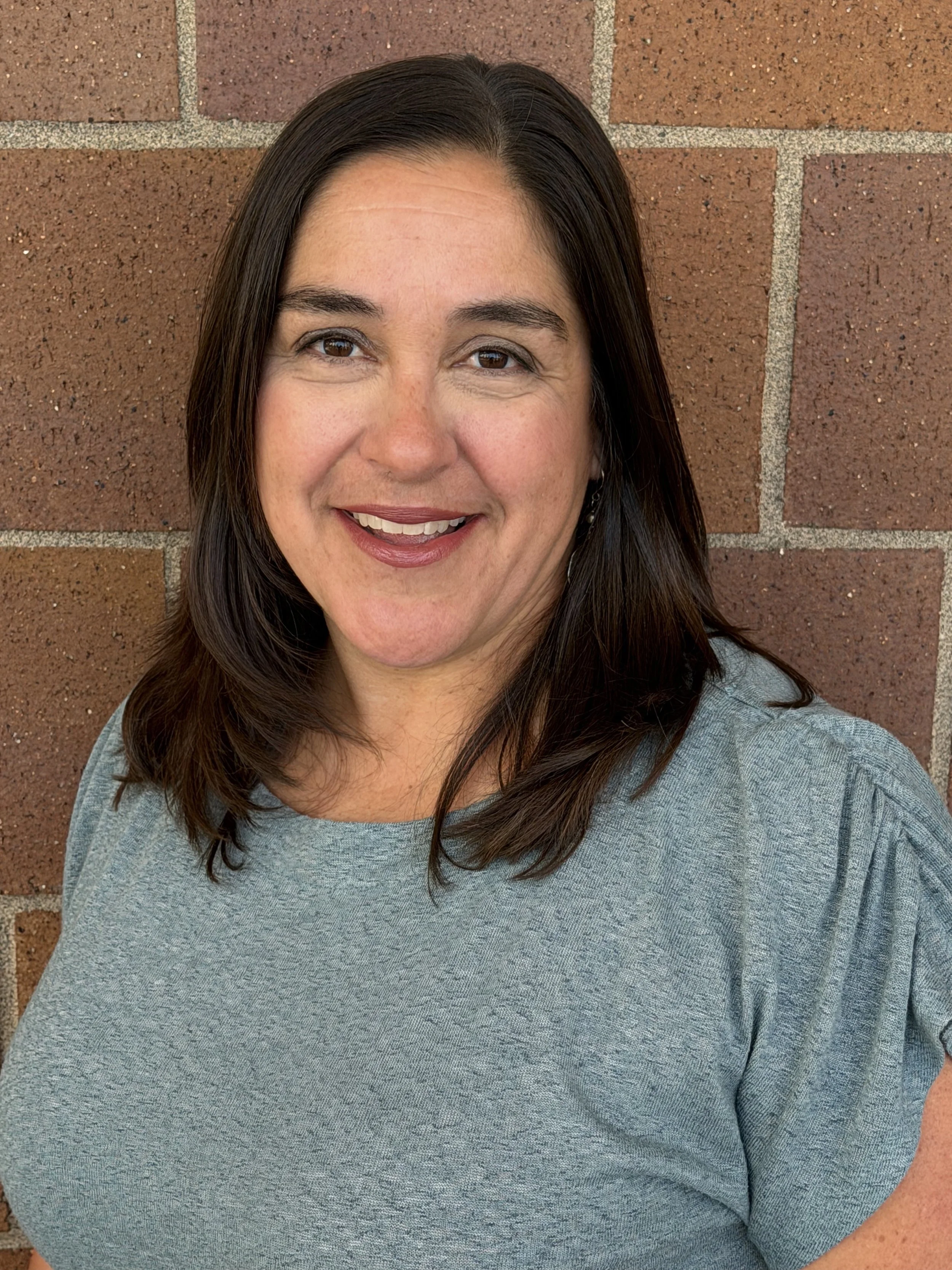 Dr. Rachell Keys stands smiling in front of a brick wall