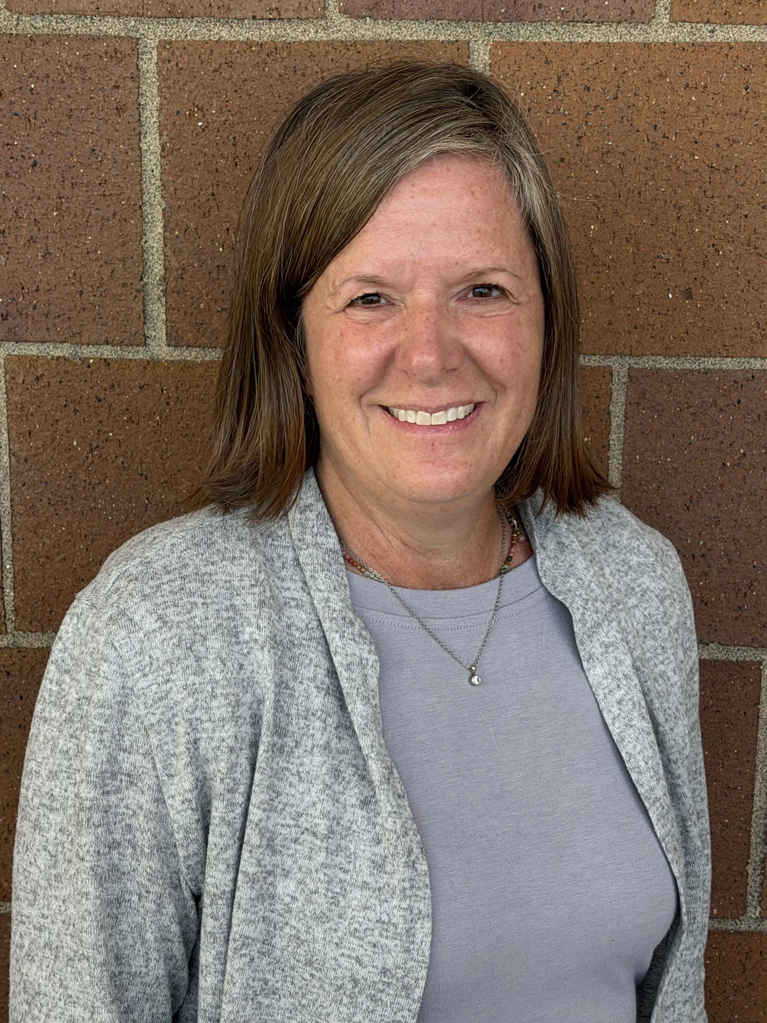 Dr. Lisa Bates stands smiling in front of a brick wall