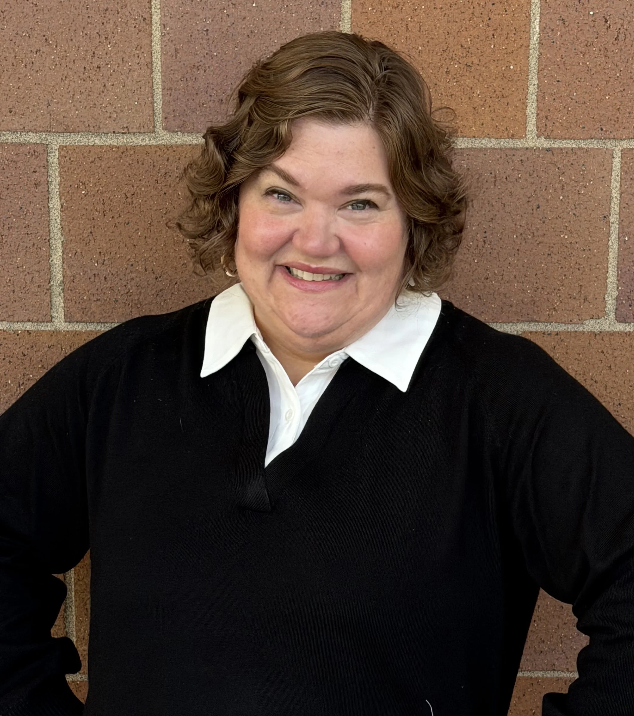 Carrie Cowan standing smiling in front of a brick wall