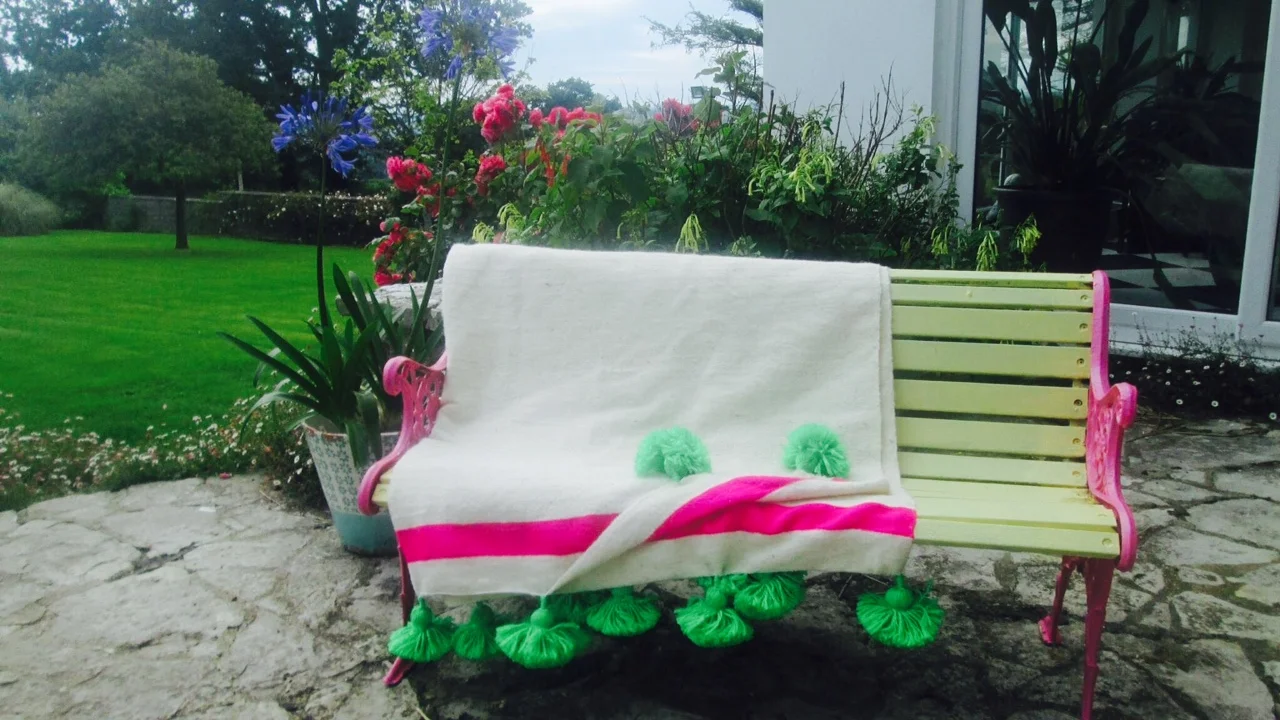 Here's a lovely pic of our wonderful Moroccan pom pom blanket in lime + fuchsia, looking good in this Devonshire garden. What came first... the bench or the blanket?.... a match made in Devon!