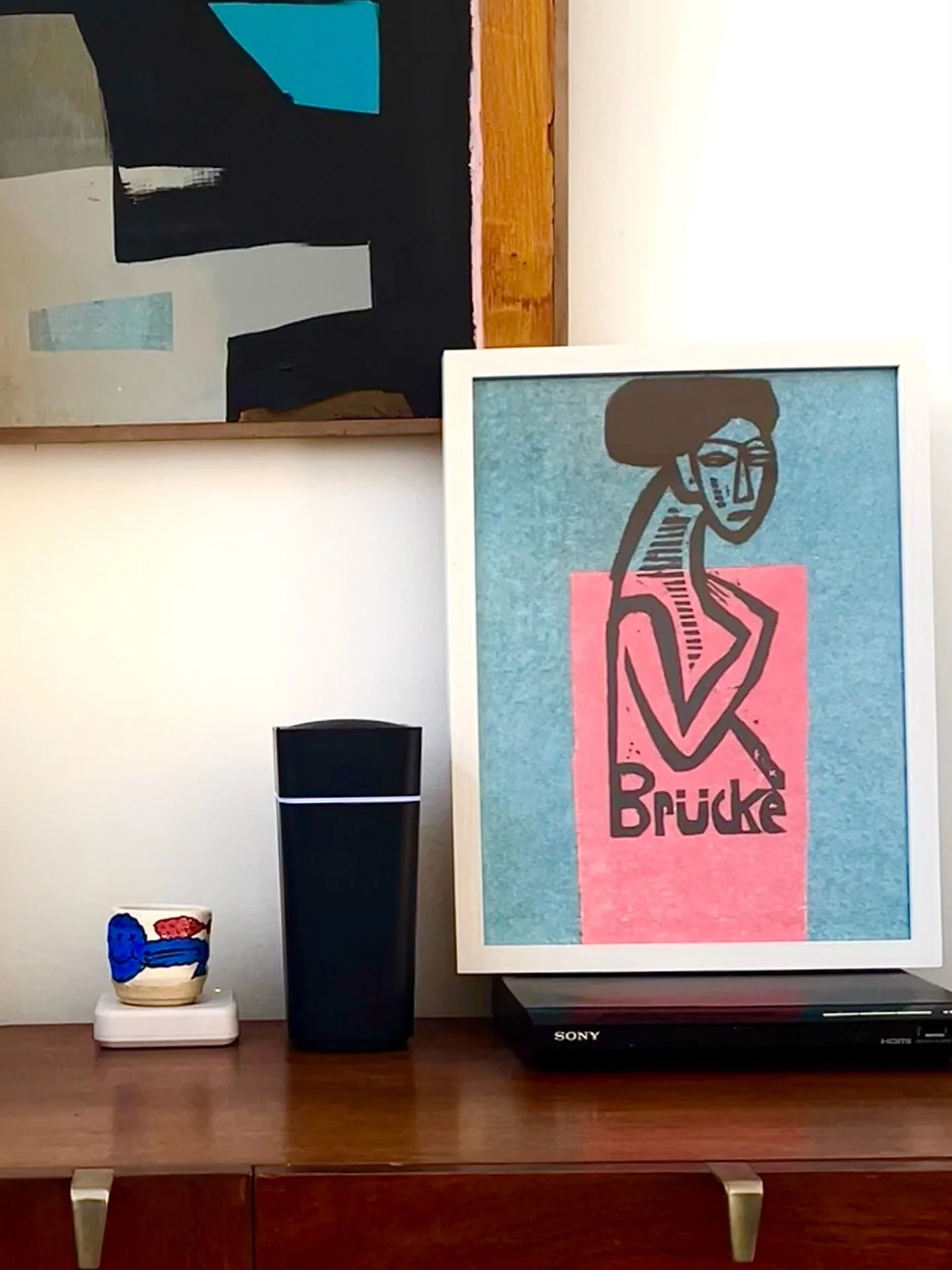 Propping art work on top of ugly essential household stuff is a thing in my house, anyone else?

Art Print Br&uuml;ke, Exhibition poster by Ernst Kirchener.
Japanese ceramic cup by @okuno_hiroshi
