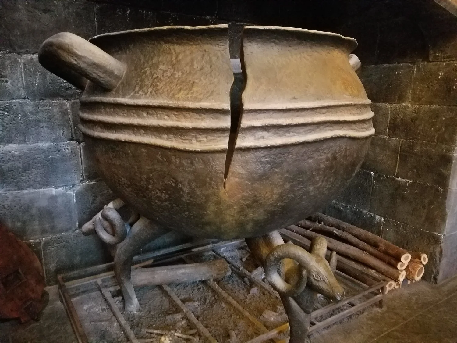 The cracked cauldron in the hearth at the Leaky Cauldron.