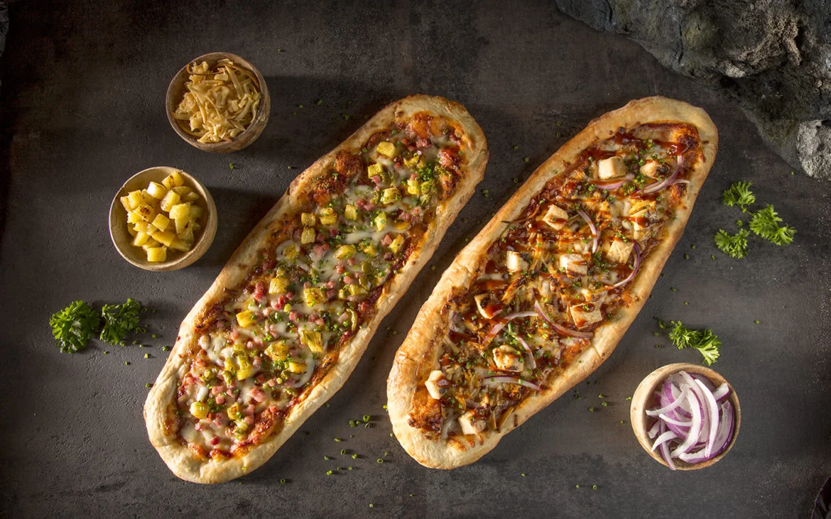 The Hawaiian Pizza and the BBQ Chicken Pizza at Whakawaiwai Eats in Volcano Bay. Image credit: Universal Orlando Resort.