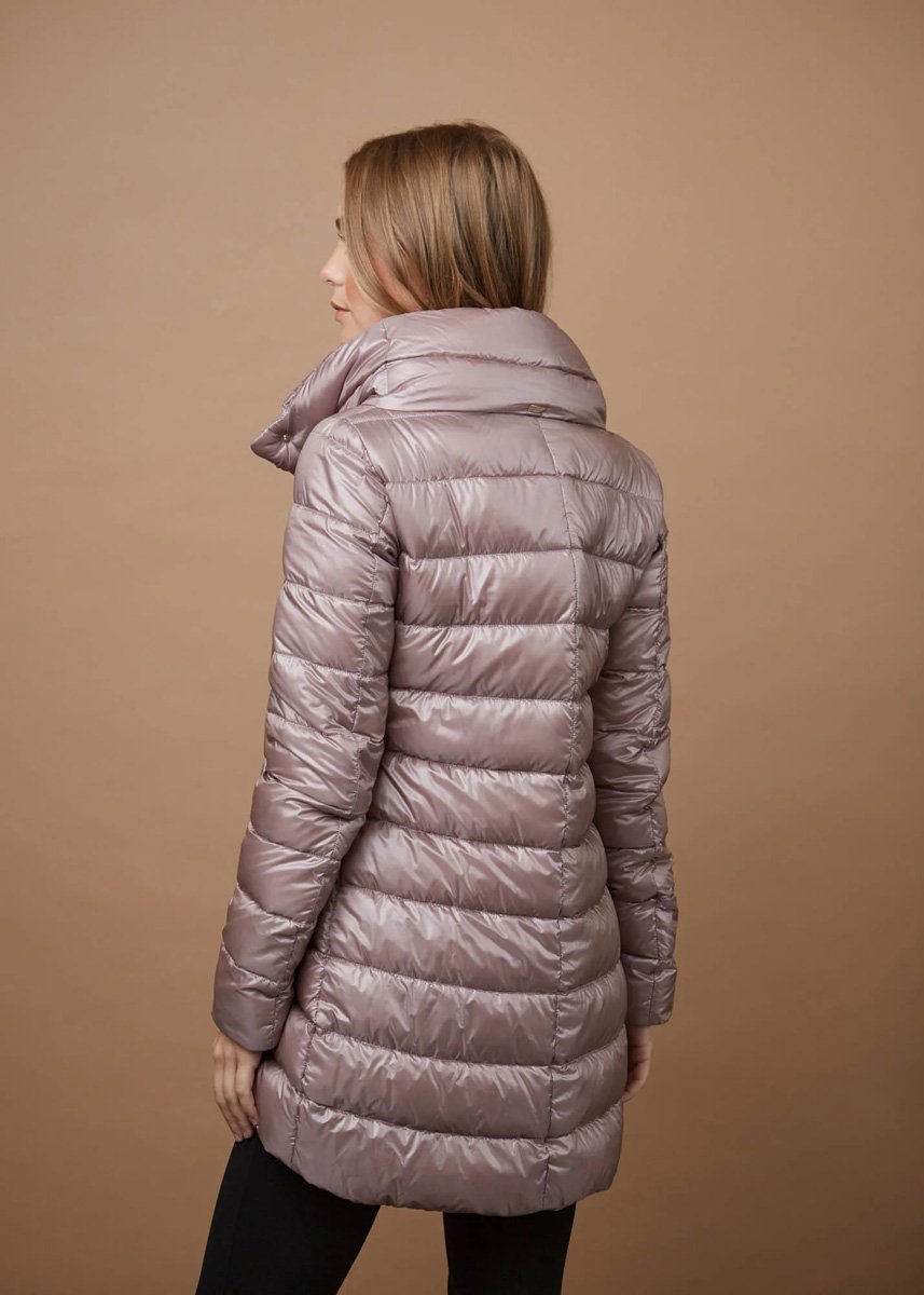 A woman wearing a shiny, puffy, beige winter coat with a high collar, standing with her back to the camera against a plain beige background.