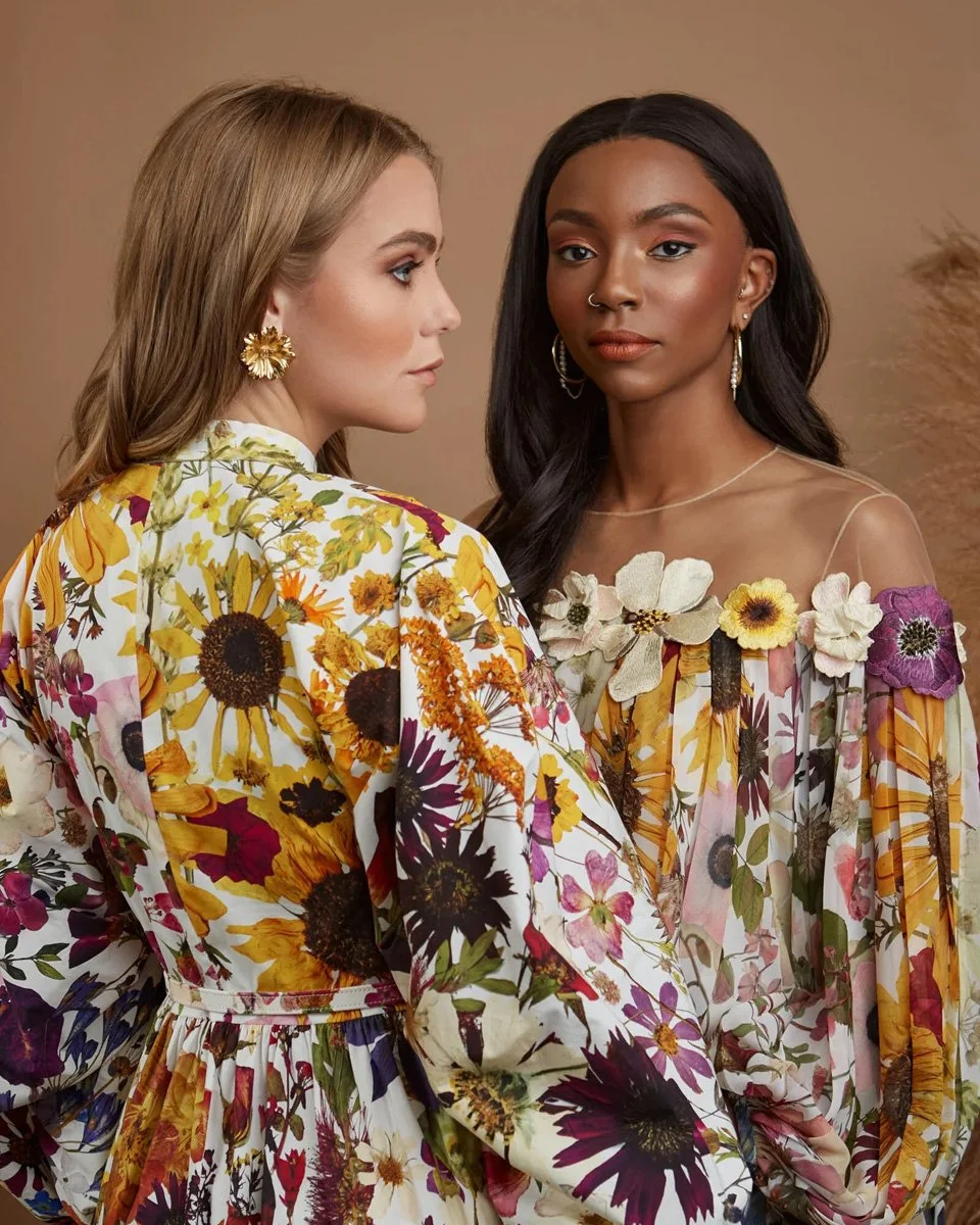 Two women wearing floral dresses with a beige background.