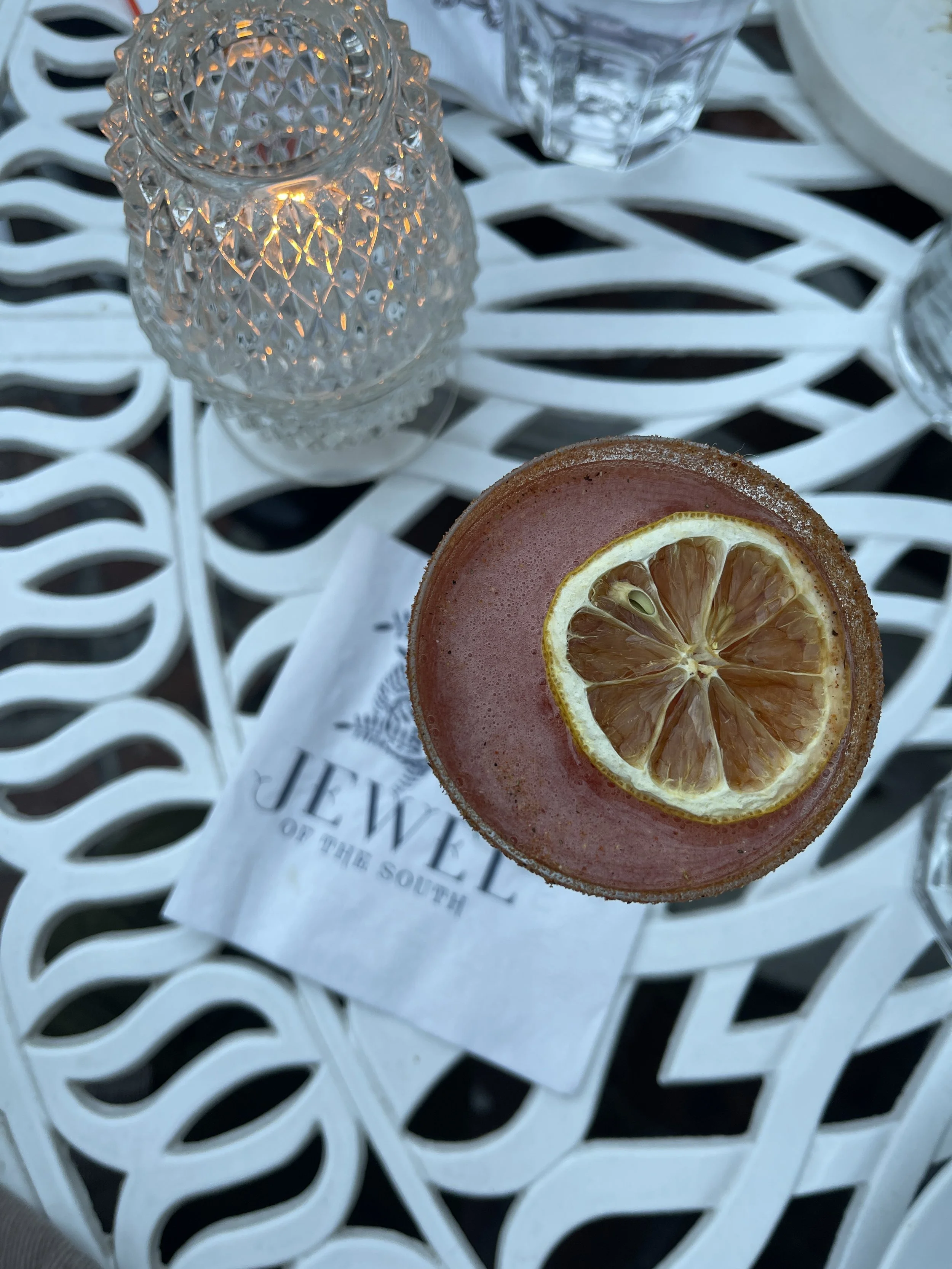 Cocktail with a dried orange wheel on a white wrought-iron table.JPG