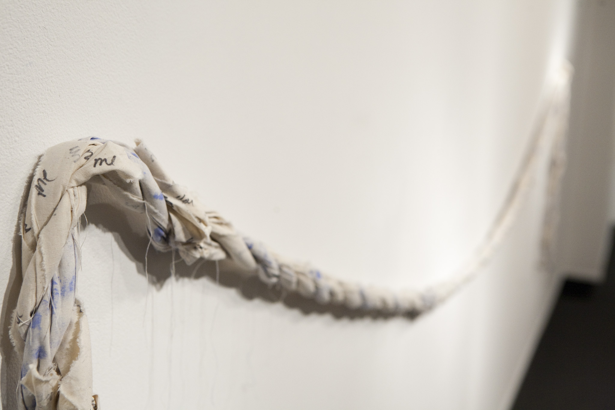 Me, You, Blue . muslin, ink, blue chalk dust. 2015. Nesbitt Gallery University of Arts and Sciences Oklahoma. Me, You, Blue was created with my partner who I have a long distance relationship with. Together we created this rope, one strand repeating “me”, another “you” and the middle strand dotted with our finger prints in blue chalk. The rope discusses both a connection, and distance.