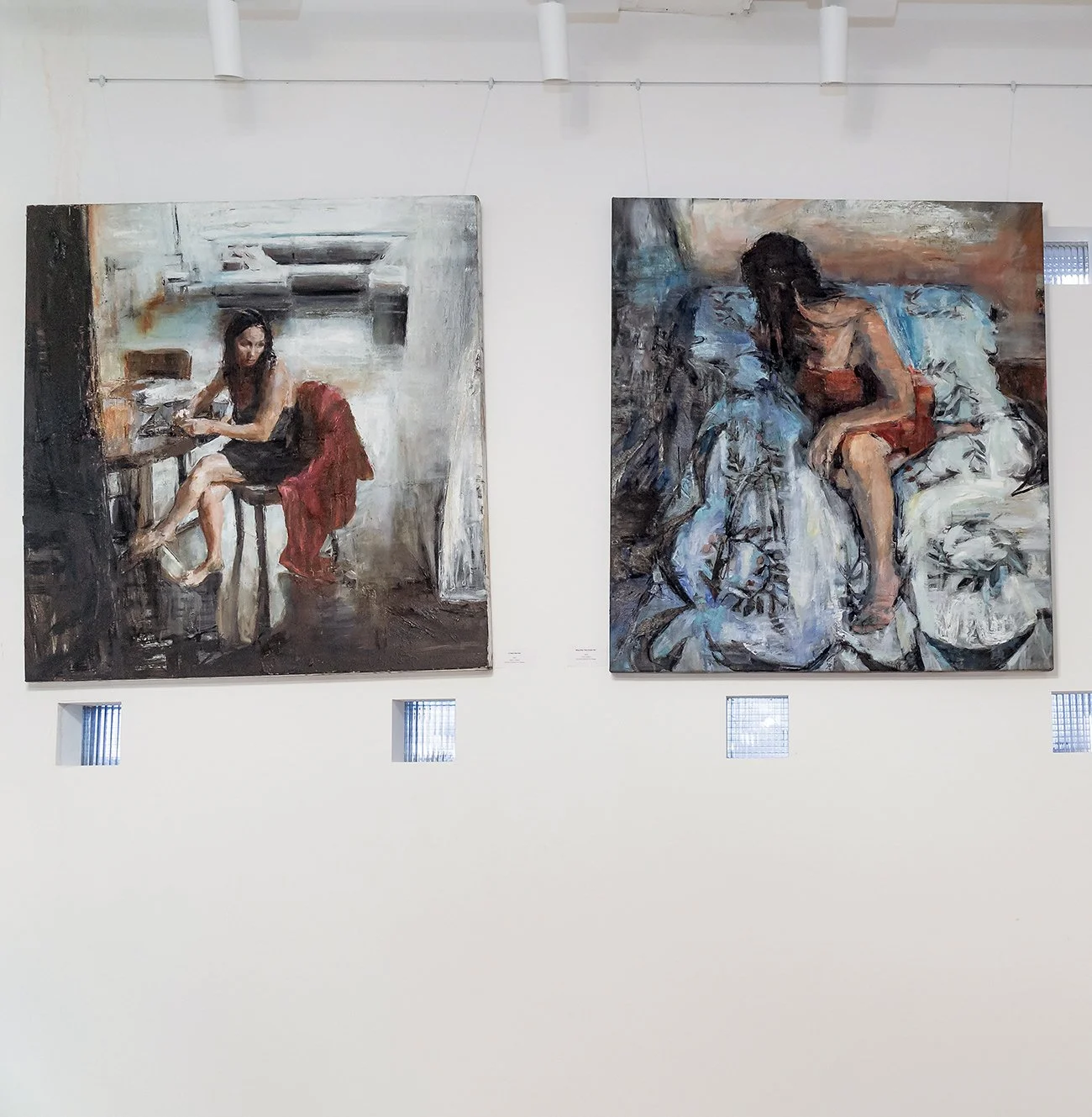 Installation view focusing on a pair of figurative paintings.