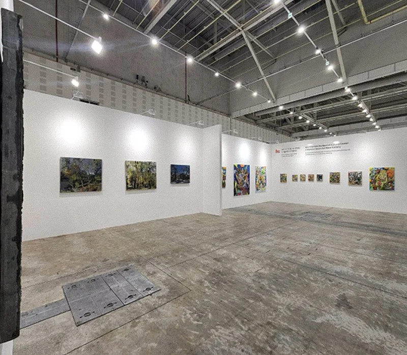 Angled installation view highlighting booth layout and paintings.