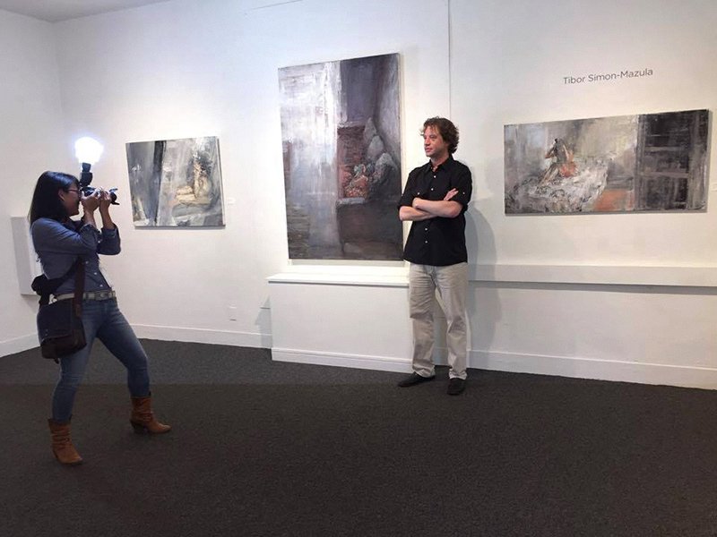 Tibor Simon-Mazula photographed with his paintings during the Emerging Artists of the Bay Area exhibition at MarinMOCA