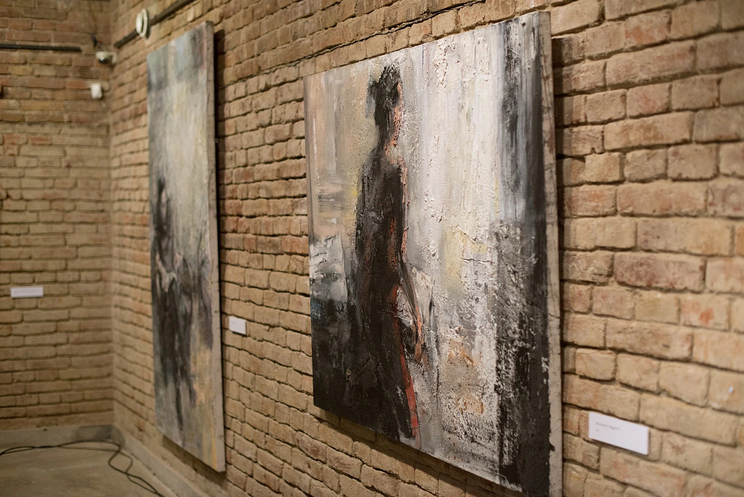 Figurative oil paintings by Tibor Simon-Mazula shown in exhibition view, presenting human figure through material surface, erosion of form, and restrained chromatic depth.