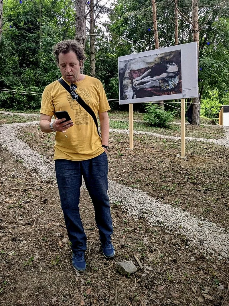Viewer encountering a painting in a forest-based open-air exhibition, Fine Art on Orfű, 2024.