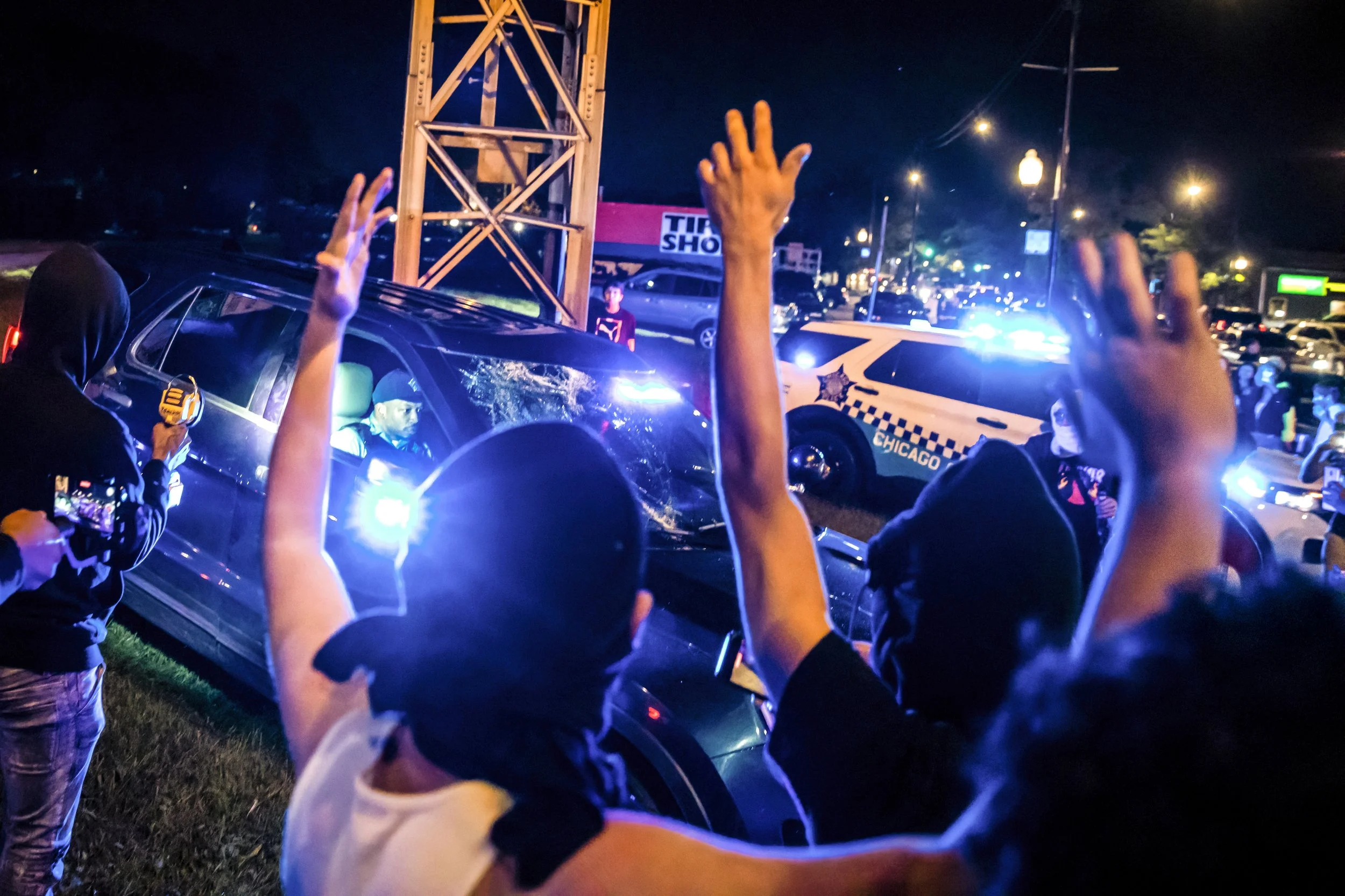  Participants and spectators harass Chicago Police Department officials after a man climbed onto their vehicle as officials attempted to break up a street takeover, where hundreds gathered to watch cars drift in circles at West 119th and South Halste