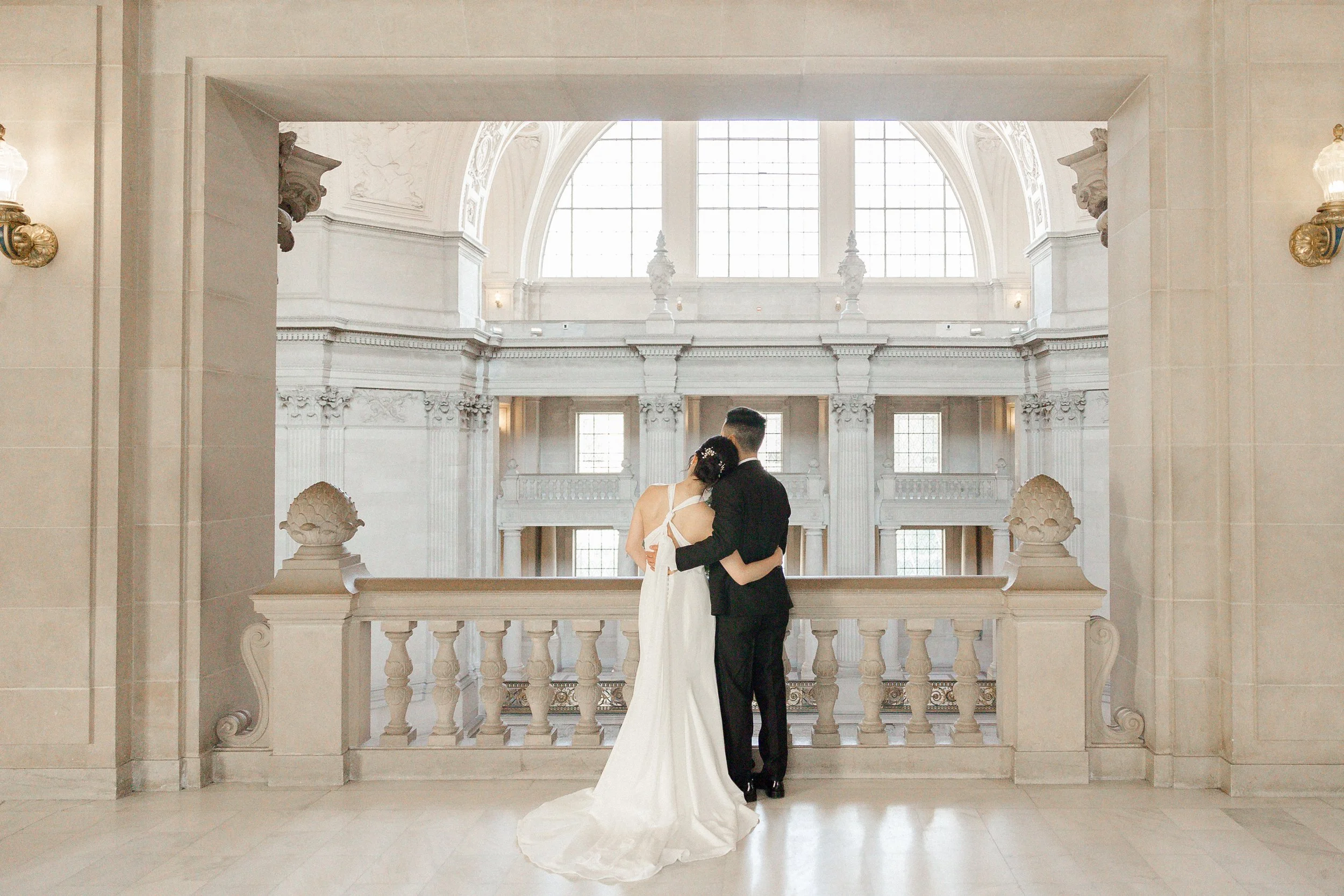 Bride and groom embrace in elegant architecture setting
