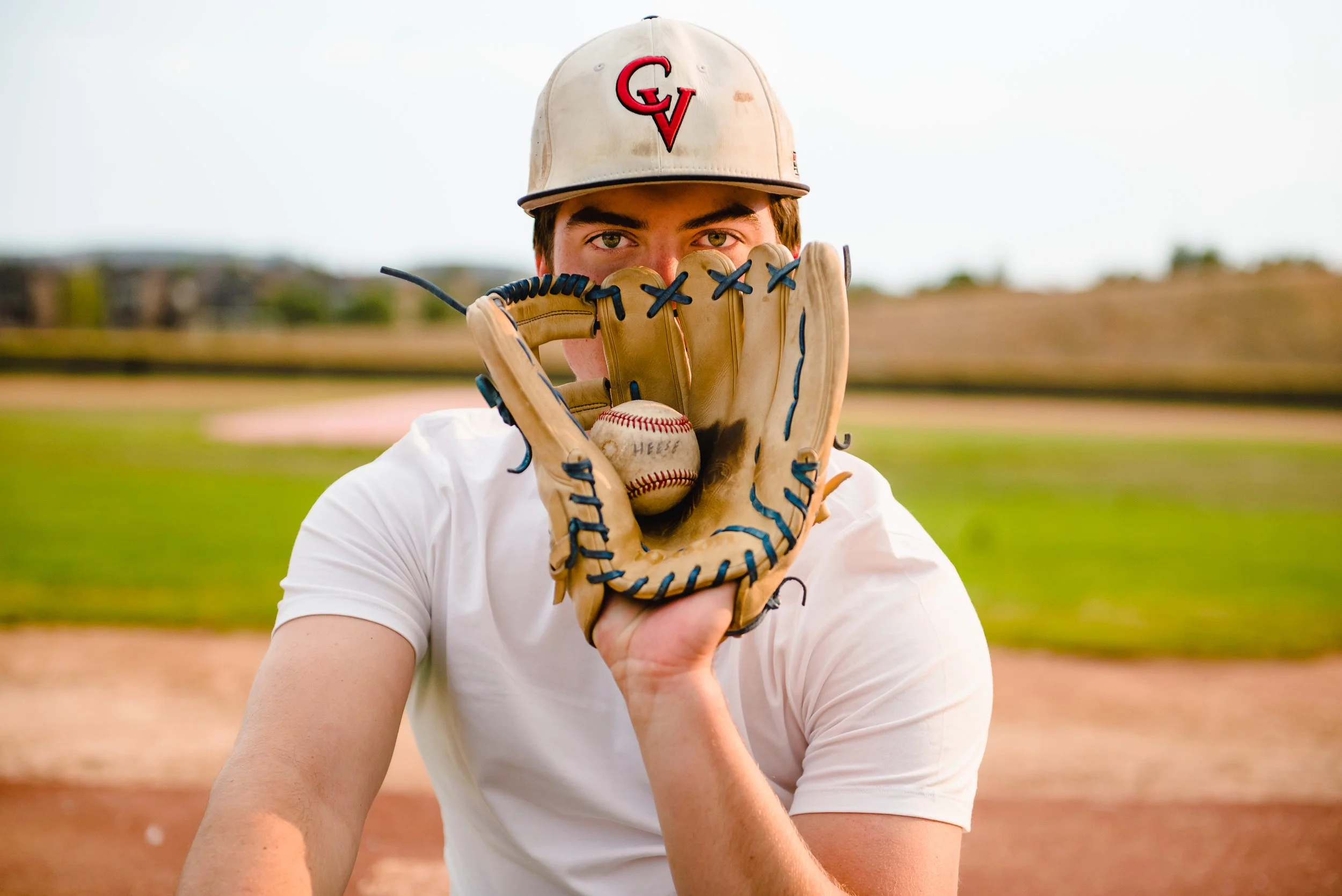 High school senior baseball player holding glove at Castle Rock baseball diamond — Denver senior sports portrait photographer Jennie Bennett Photography
