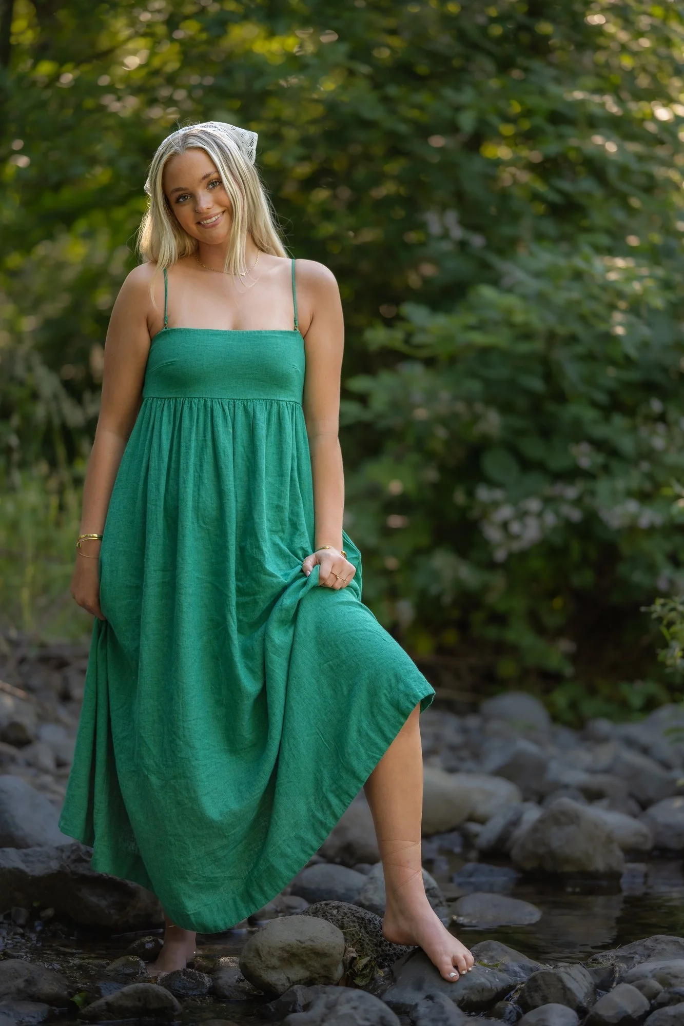 High school senior in a green sundress walking by a river in Colorado, spring senior photos by Castle Rock photographer Jennie Bennett Photography