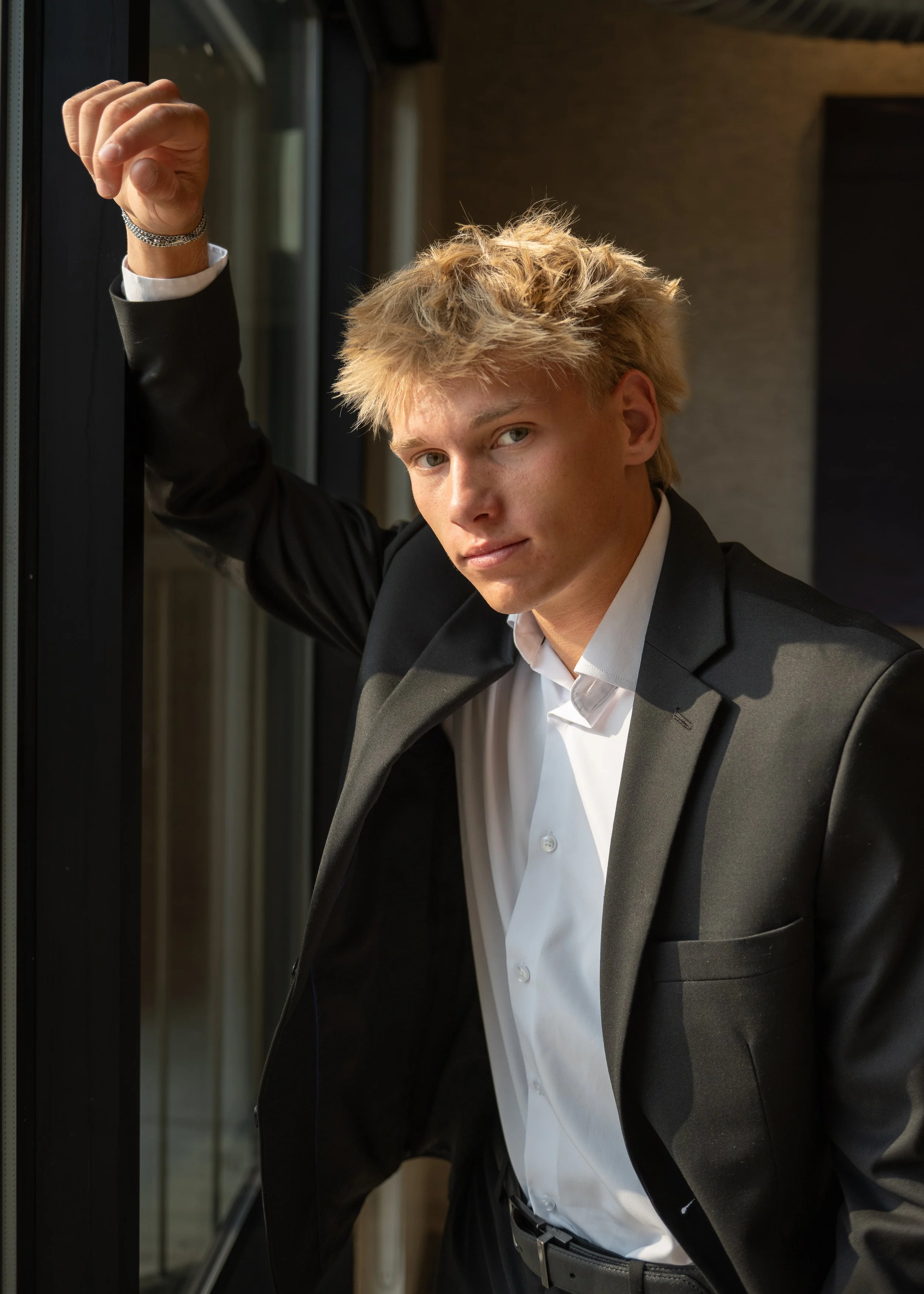 High school senior boy in black suit leaning against wall — Denver male senior portrait photographer Jennie Bennett Photography