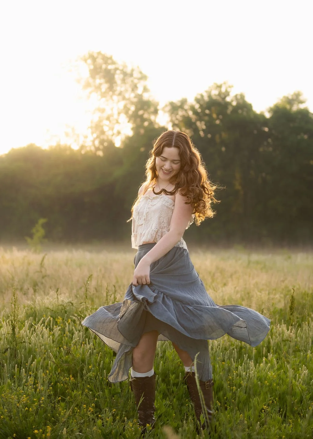 High school senior girl twirling a flowy blue skirt in a sunlit grass field at golden hour, Colorado senior photos by Castle Rock photographer Jennie Bennett Photography