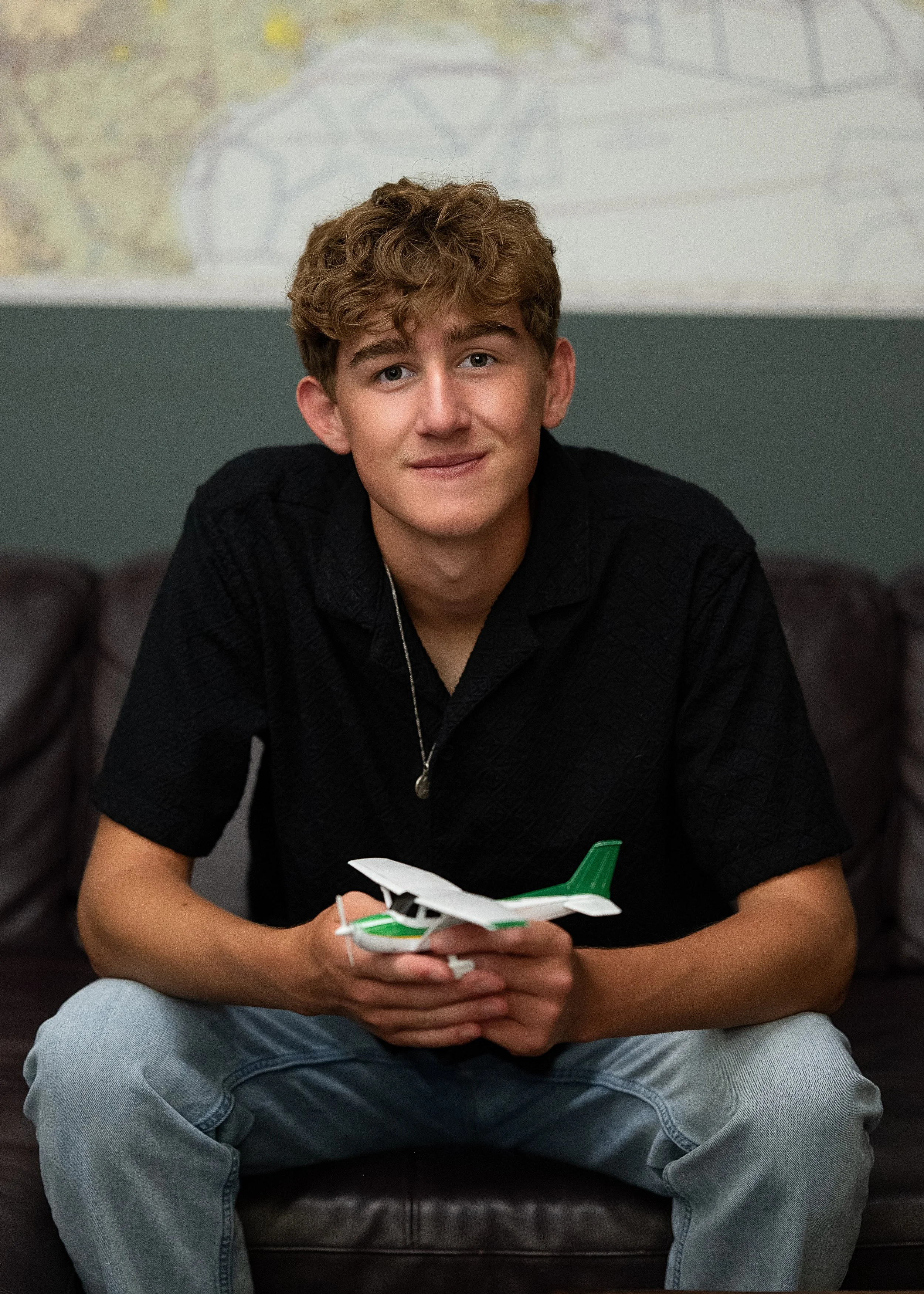 High school senior guy holding a model airplane in front of a vintage map, personalized senior portrait in Centennial, Colorado