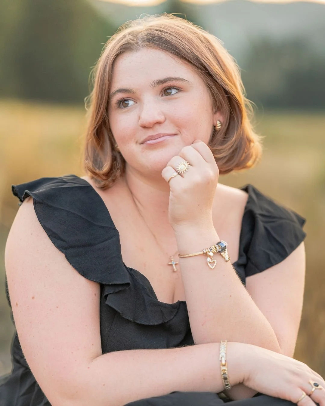 High school senior girl sitting on a quiet mountain road surrounded by pine trees, Bailey, Colorado senior portrait session.