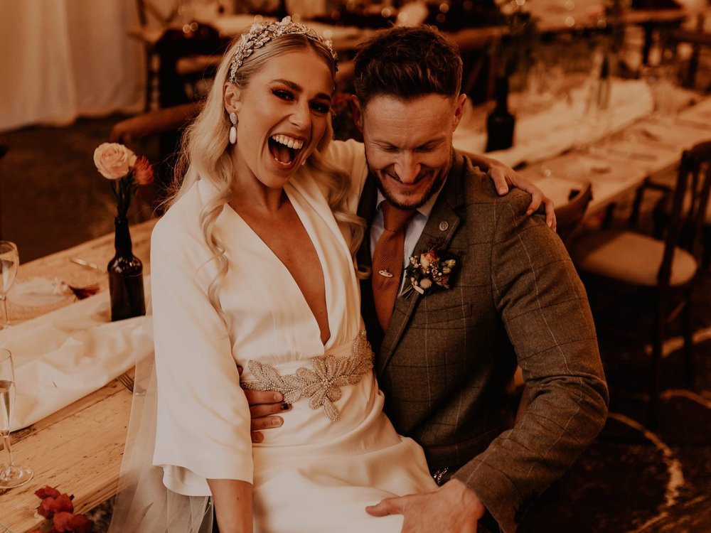 Lucy laughs while sitting on Jody's lap during the wedding reception