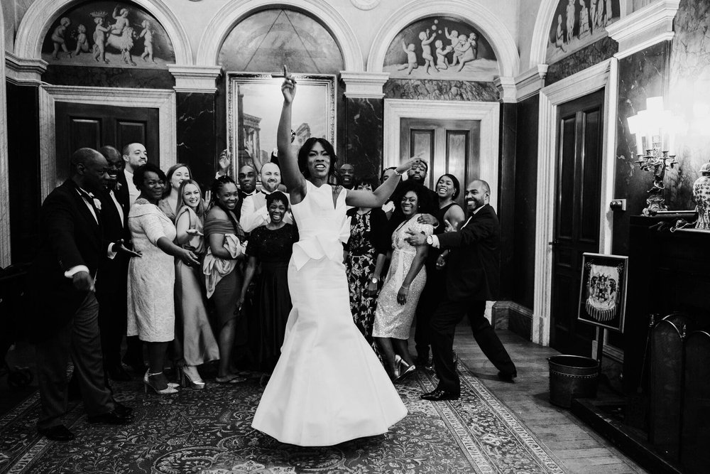  Meisha has one hand in the air as she dances in front of a group of family and friends. 