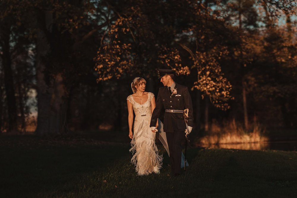  Emma and Sam walk hand in hand through the grounds of their wedding venue during golden hour.  