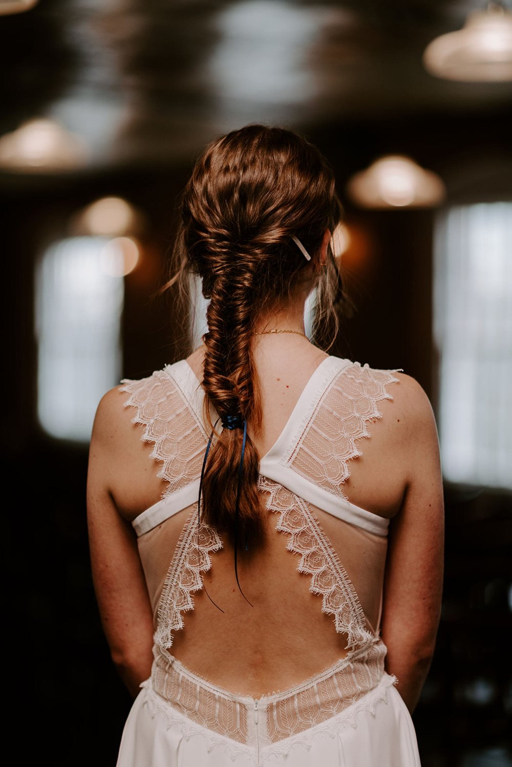  The back of Emma’s dress is made of four lace panels (the lace has a pointy, scalloped edge) that meet in the centre at the top of her back. Her long brunette hair is in a fishtail plait. 